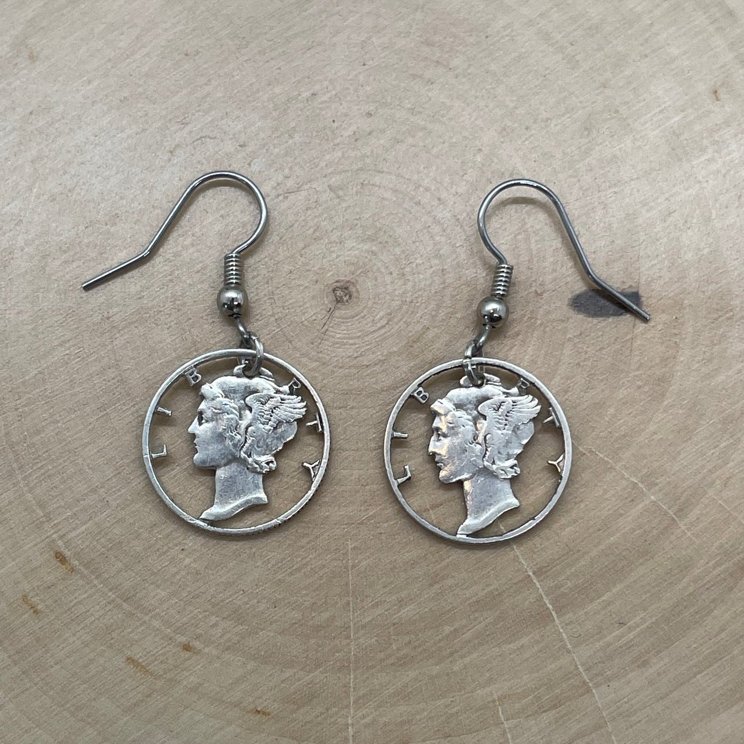 U.S. Mercury Dime Silver Hand Cut Coin Earrings on a light wood round. - Mountainstruck Coin Jewelry
