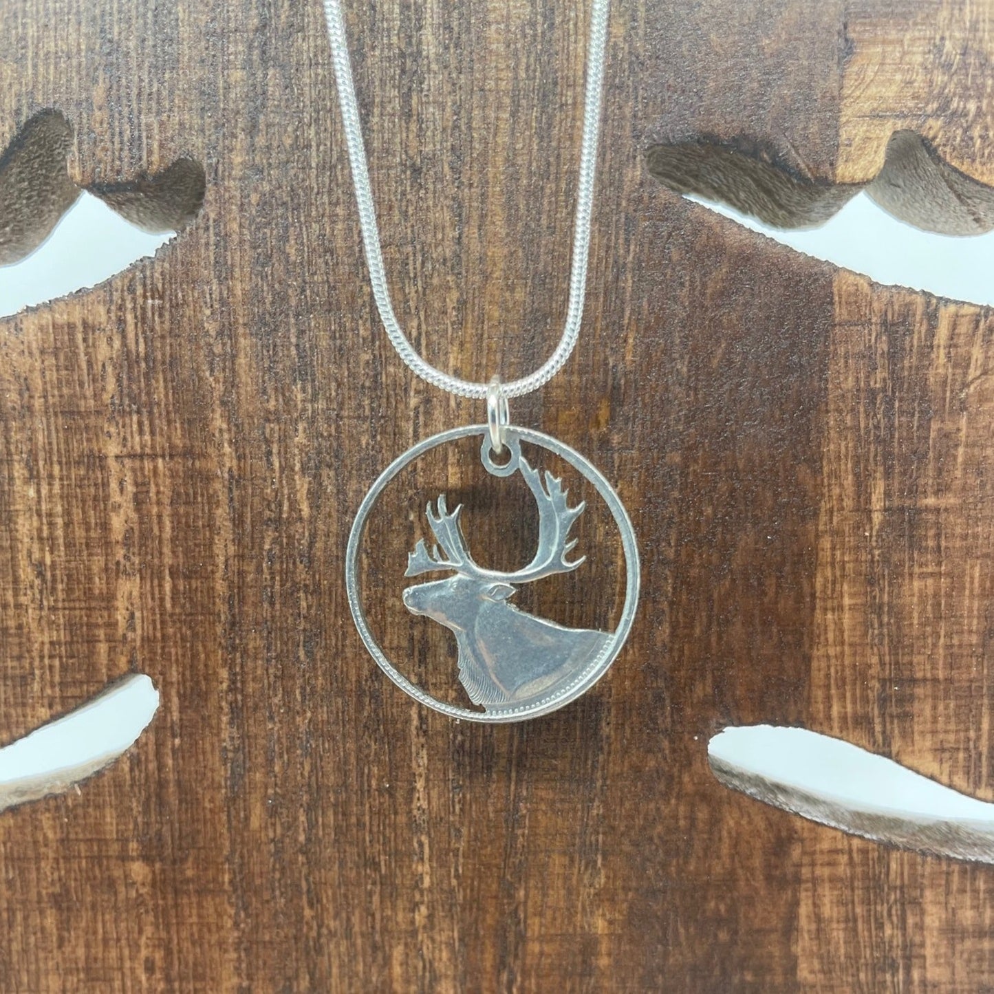 Canada Caribou 25 Cents hand cut coin necklace with a snake chain on a wood background. - Mountainstruck Coin Jewelry