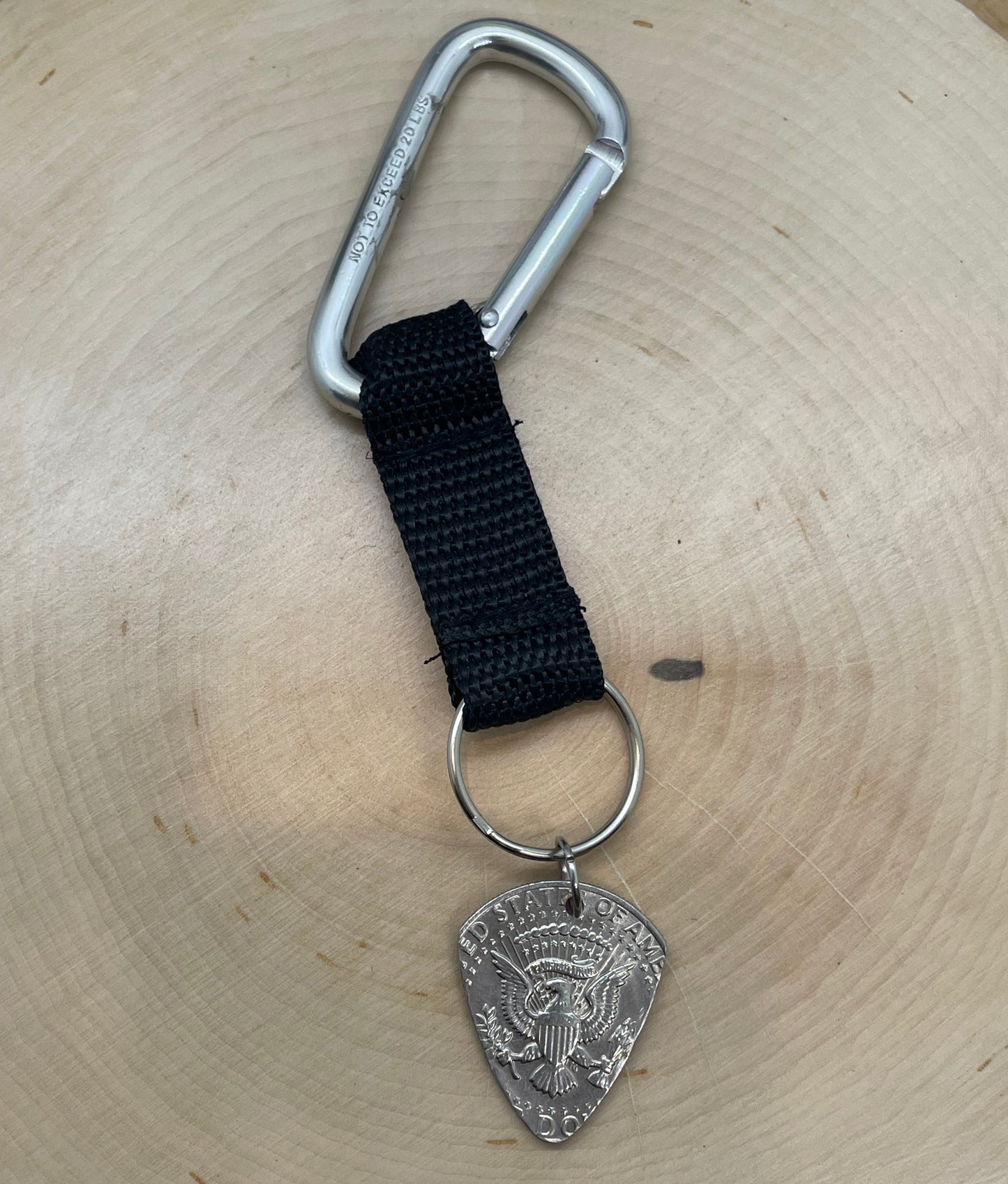 Guitar Pick U.S. Half Dollar Keychain with a black strap on a light wood round. - Mountainstruck Coin Jewelry