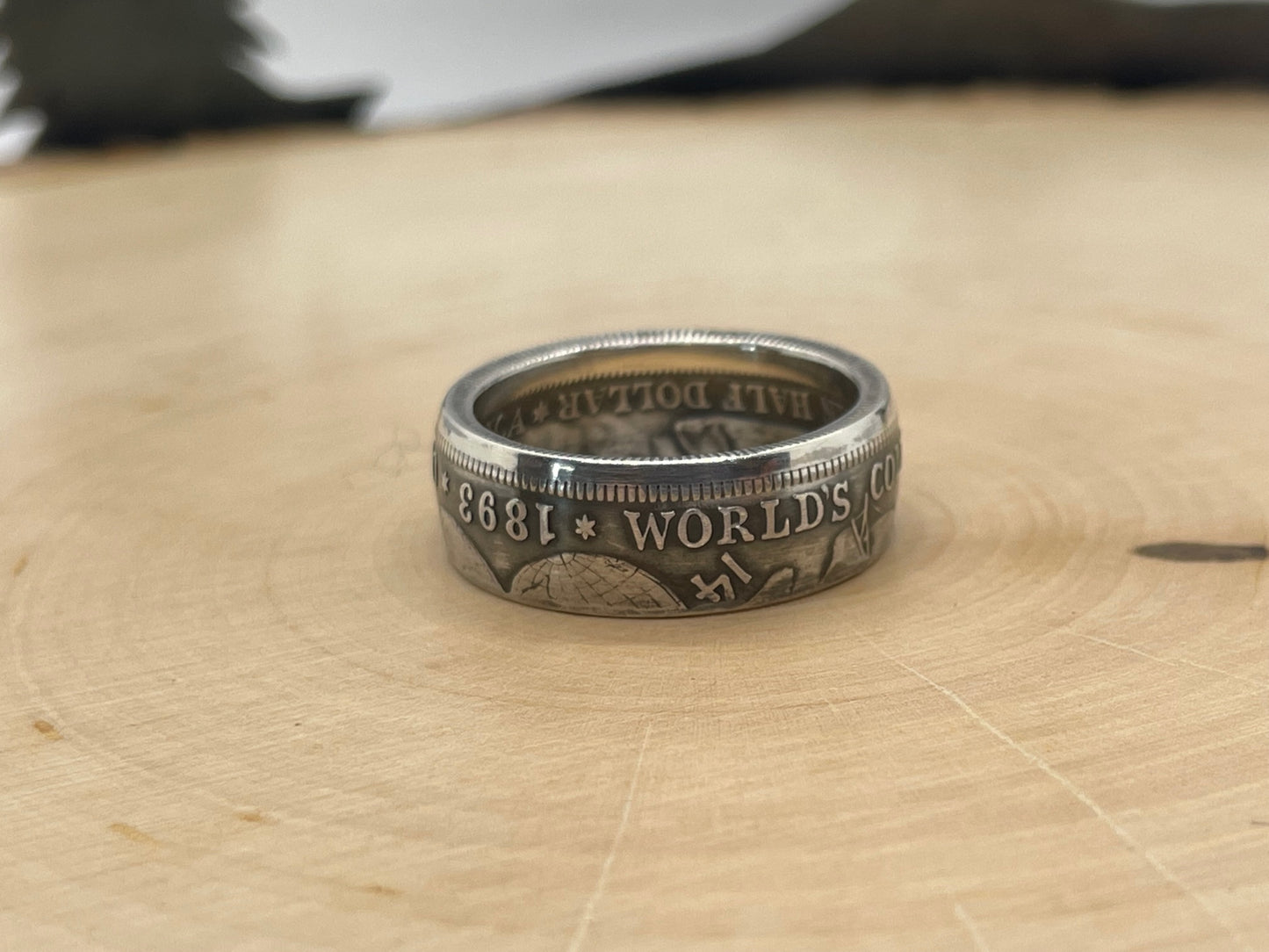 U.S. 1892-1893 Chicago Columbus Silver Half Dollar Coin Ring (patina) on a light wood round.