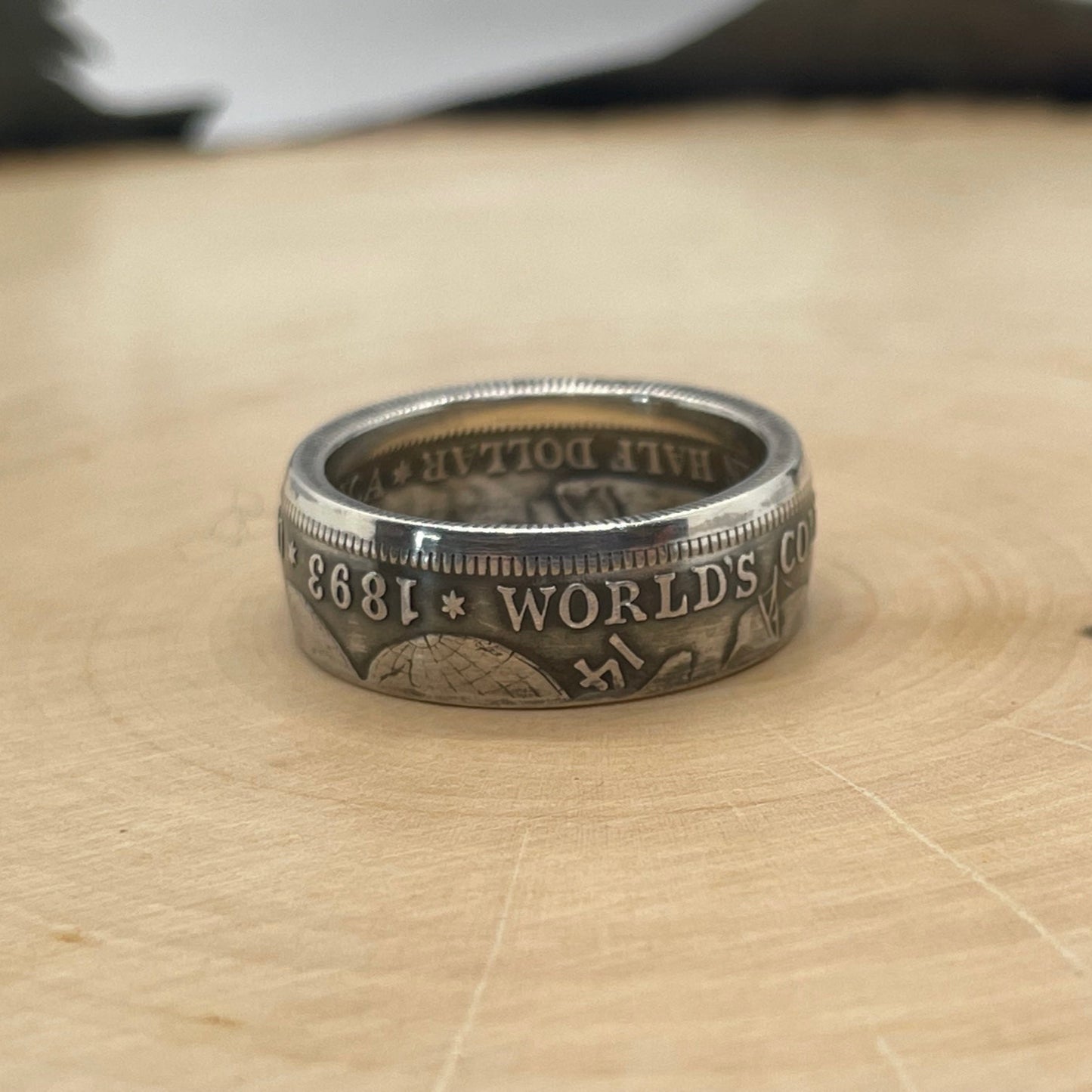 U.S. 1892-1893 Chicago Columbus Silver Half Dollar Coin Ring (patina) on a light wood round.