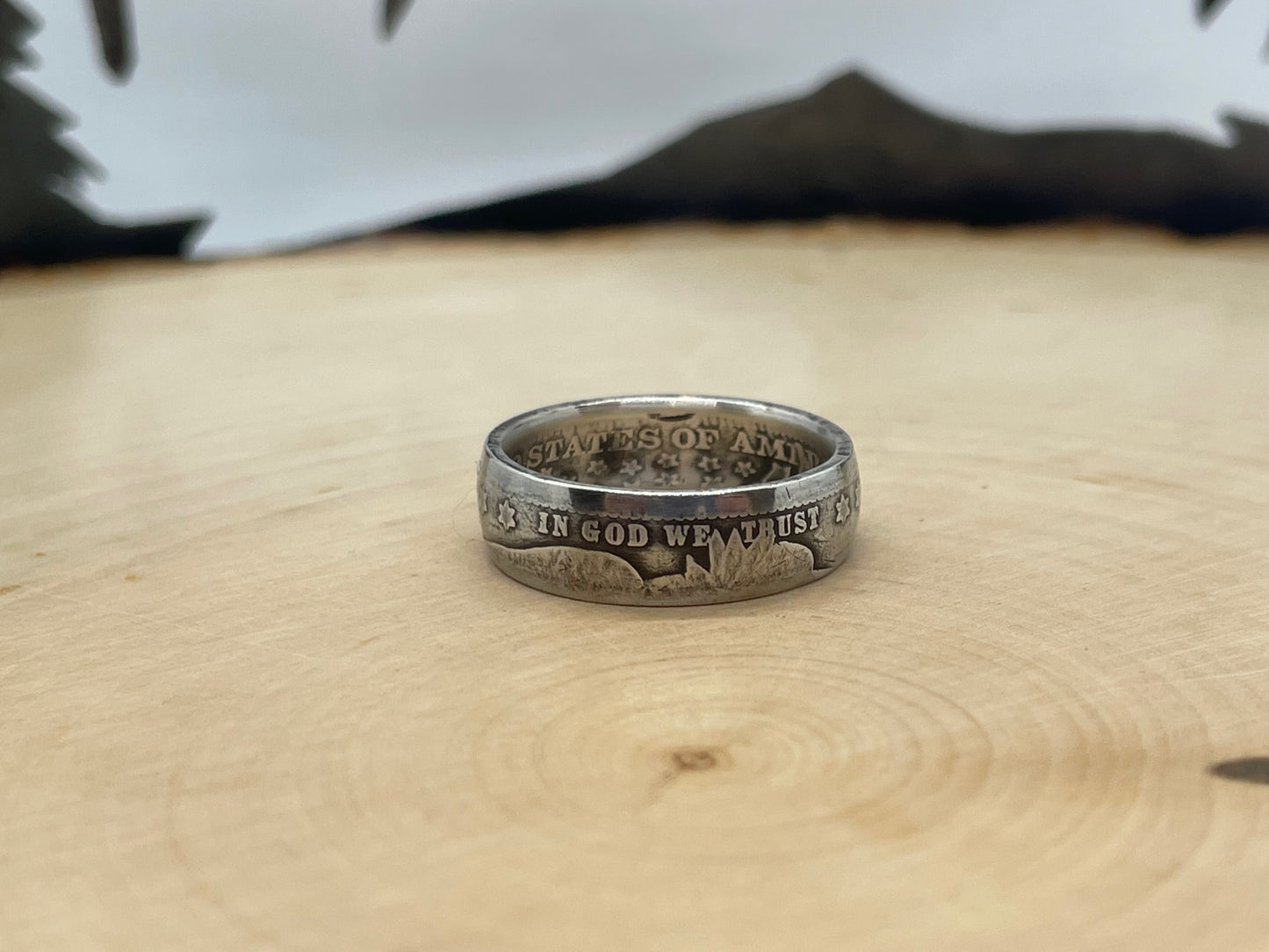 Barber Silver Quarter Coin Ring (front) on a light wood round with mountain outline in the background. - Mountainstruck Coin Jewelry