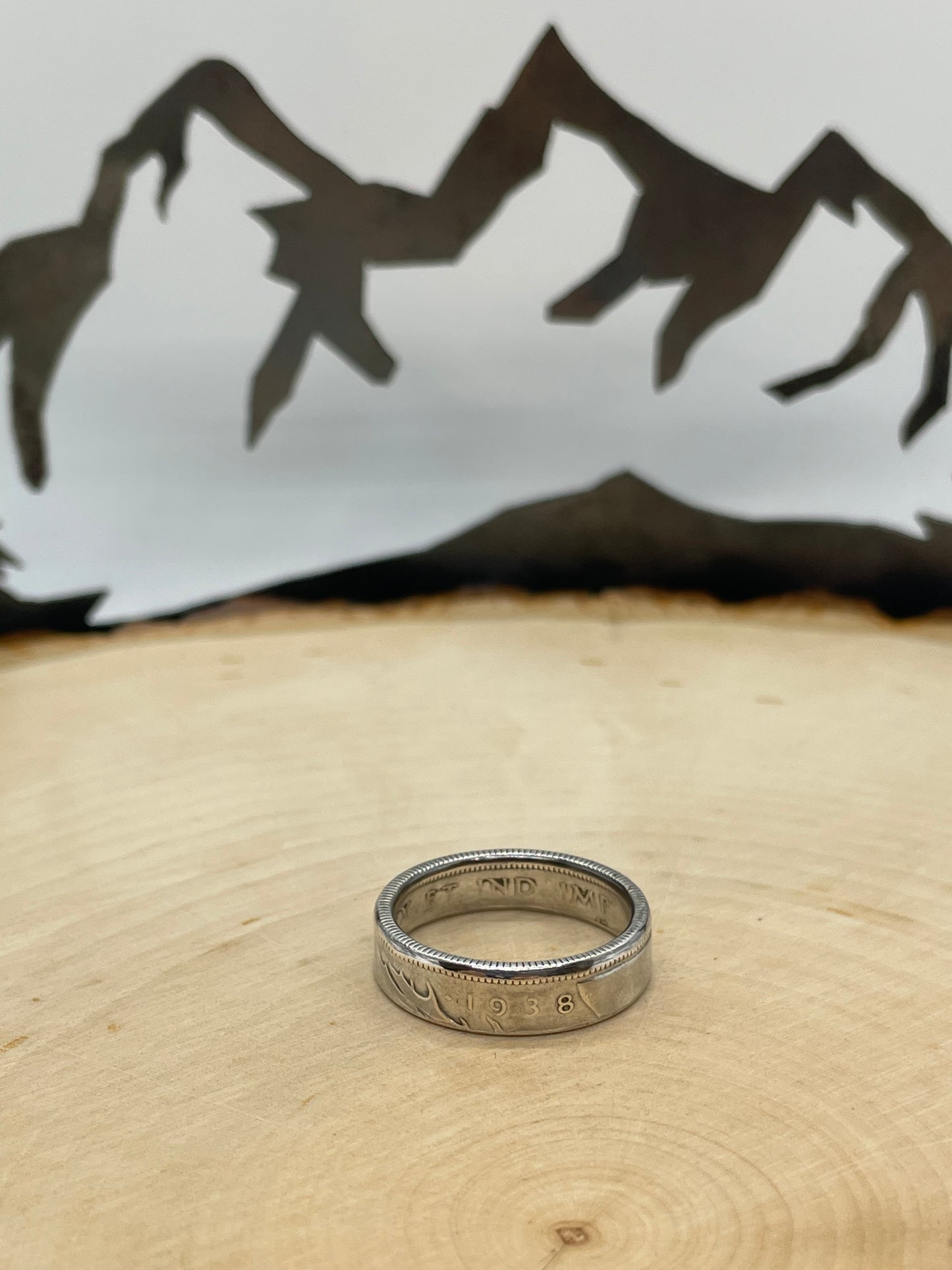 Canada 25 Cents Silver Coin Ring on a light wood round with a mountain outline background. - Mountainstruck Coin Jewelry