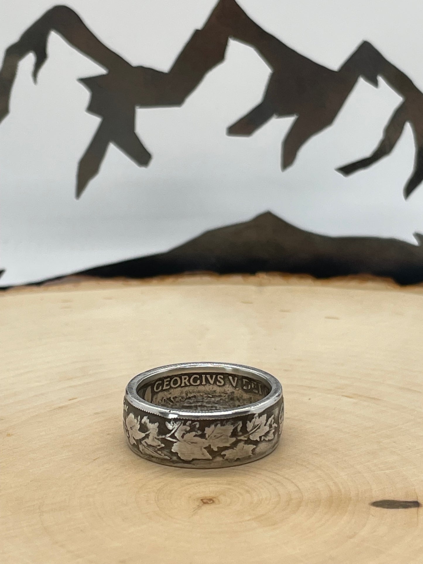 Canada 50 Cents Maple Leaf Silver Coin Ring on a light wood round with a mountain outline background. - Mountainstruck Coin Jewelry