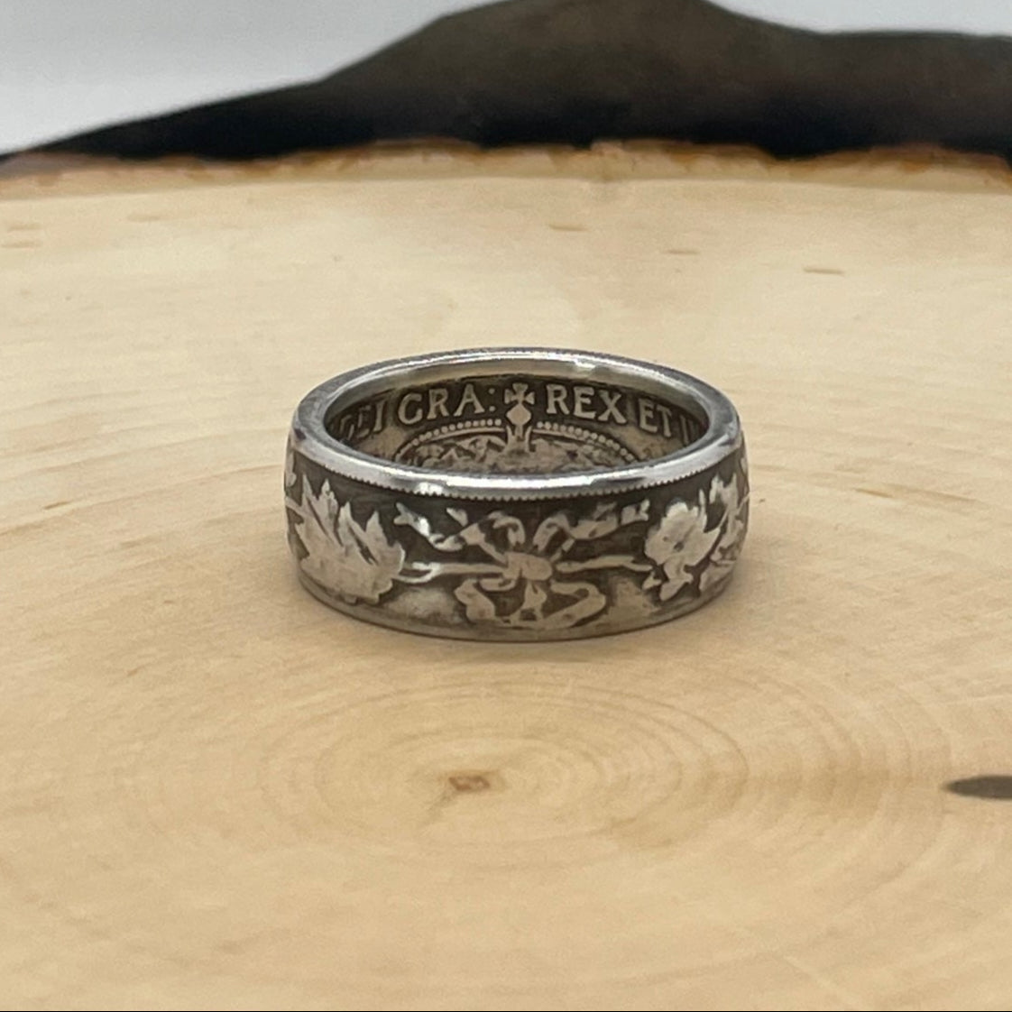 Canada 50 Cents Maple Leaf Silver Coin Ring on a light wood round with a mountain outline background. - Mountainstruck Coin Jewelry