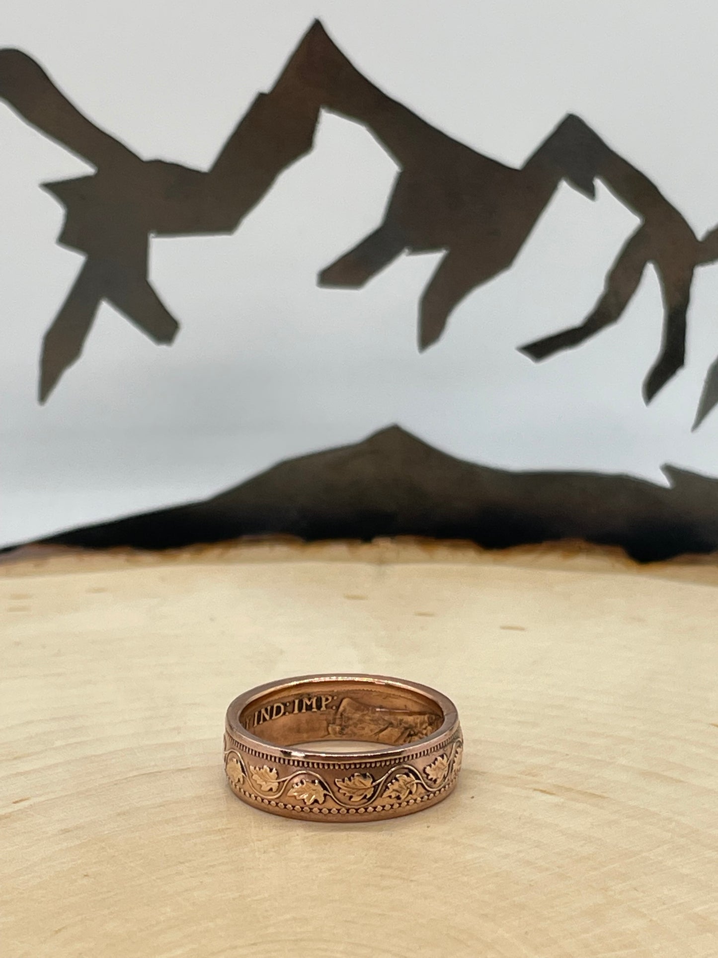 Canada Large Cent Leaf Coin Ring on a light wood round with a mountain outline background. - Mountainstruck Coin Jewelry