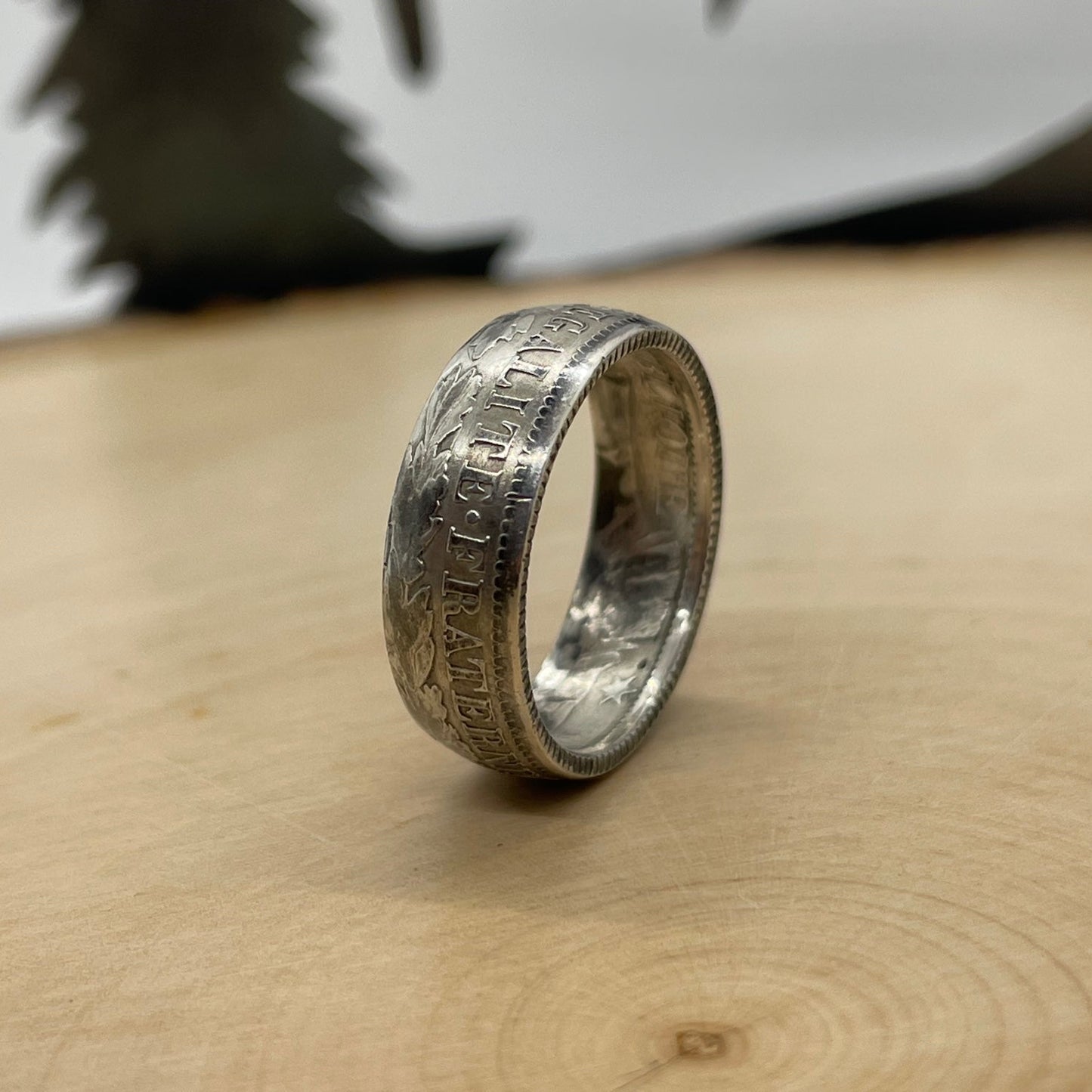 France 1 Franc Silver Coin Ring on its side on a light wood round with a mountain outline background. - Mountainstruck Coin Jewelry