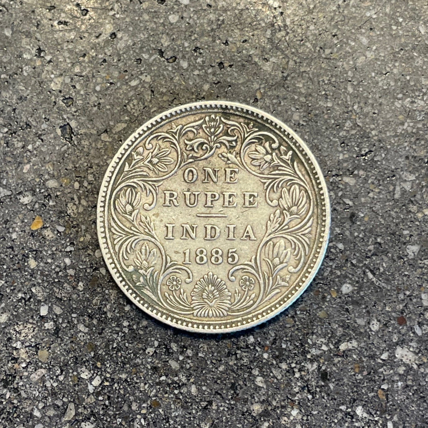 India 1 Rupee Silver Coin (Rare, Victorian) back on a concrete background. - Mountainstruck Coin Jewelry