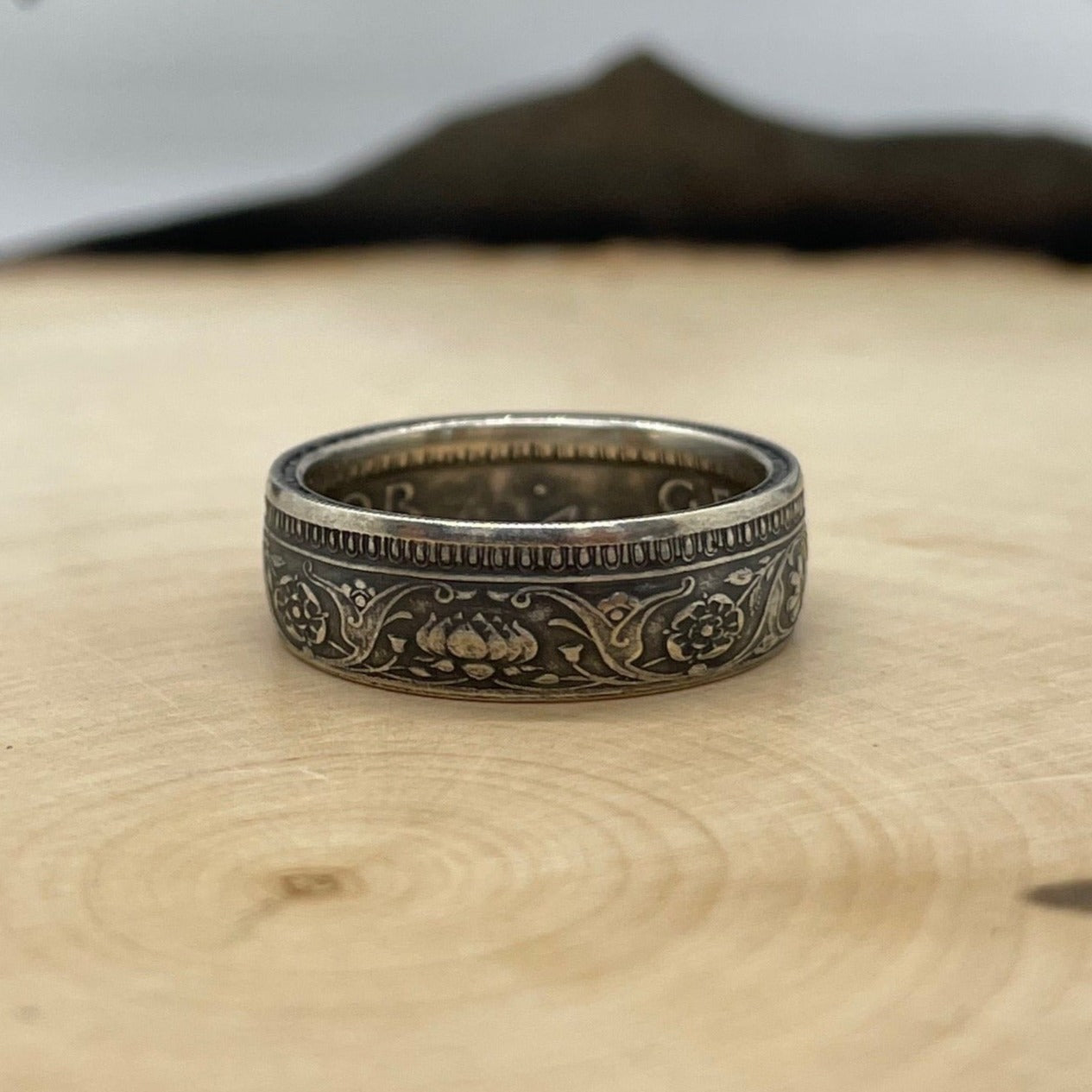 India Half Rupee Silver Coin Ring on a light wood round with mountain outline in the background. - Mountainstruck Coin Jewelry