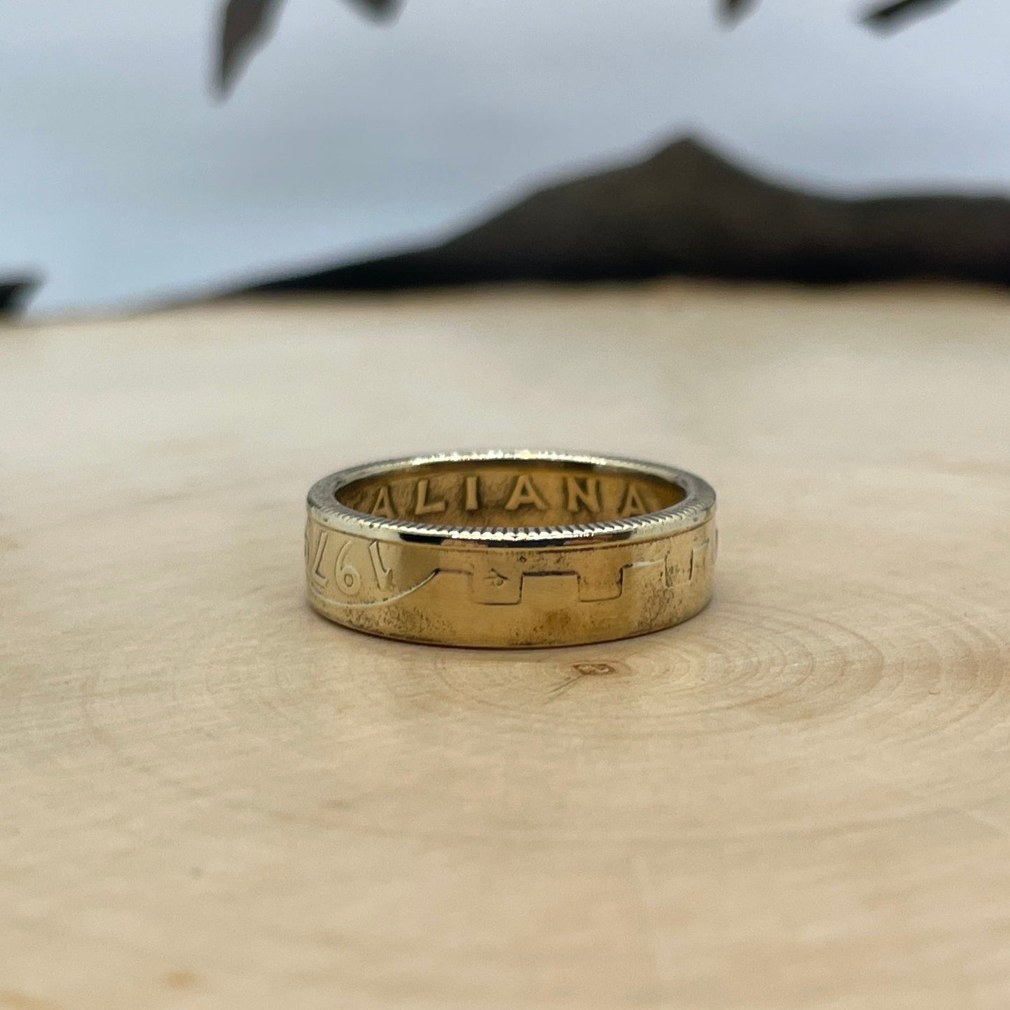 Italy 200 Lire Coin Ring on a light wood round with mountain outline in background. - Mountainstruck Coin Jewelry