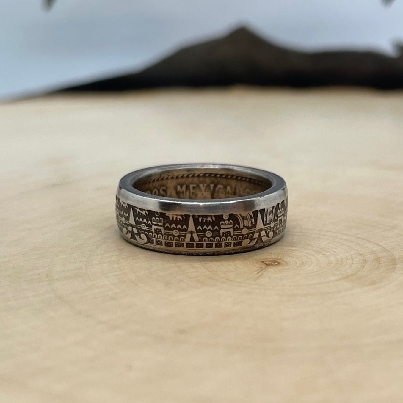 Mexico 10 Centavos Coin Ring on a light wood round with mountain outline in the background. - Mountainstruck Coin Jewelry