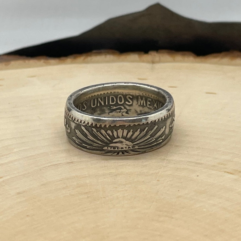 Mexico 50 Centavos Silver Coin Ring (Rare) on a light wood round with mountain outline in the background. - Mountainstruck Coin Jewelry