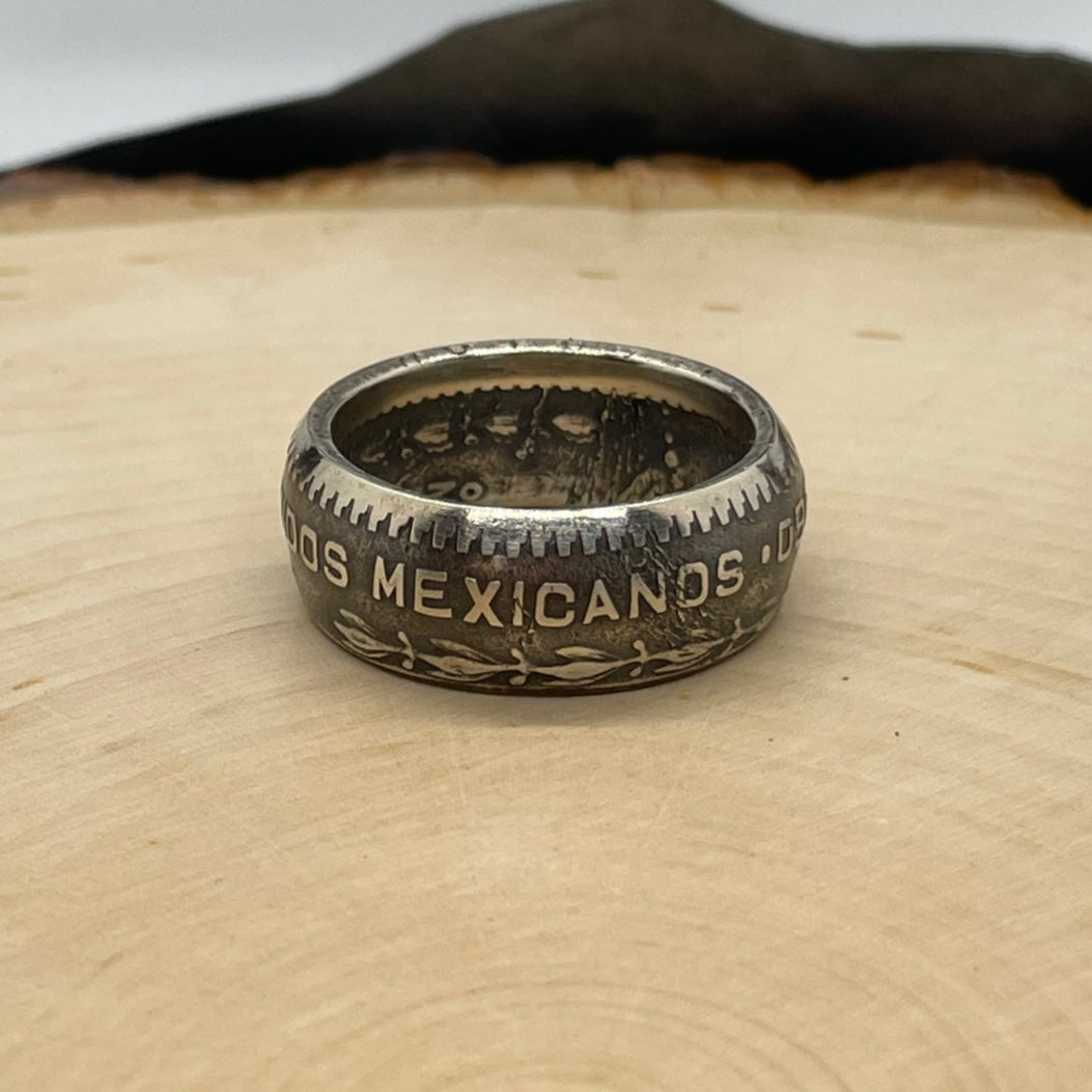 Mexico Silver Peso Coin Ring on a light wood round with mountain outline in the background. - Mountainstruck Coin Jewelry