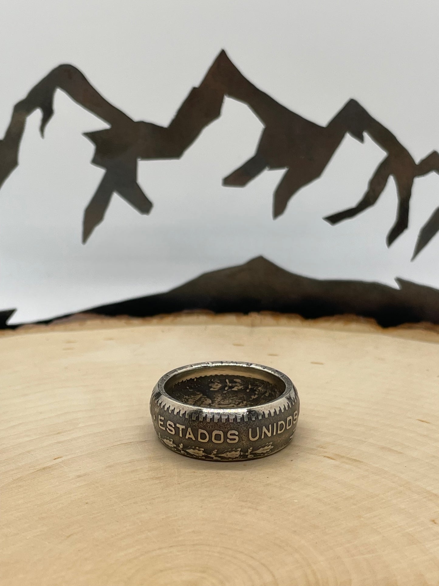 Mexico Silver Peso Coin Ring on a light wood round with mountain outline in the background. - Mountainstruck Coin Jewelry