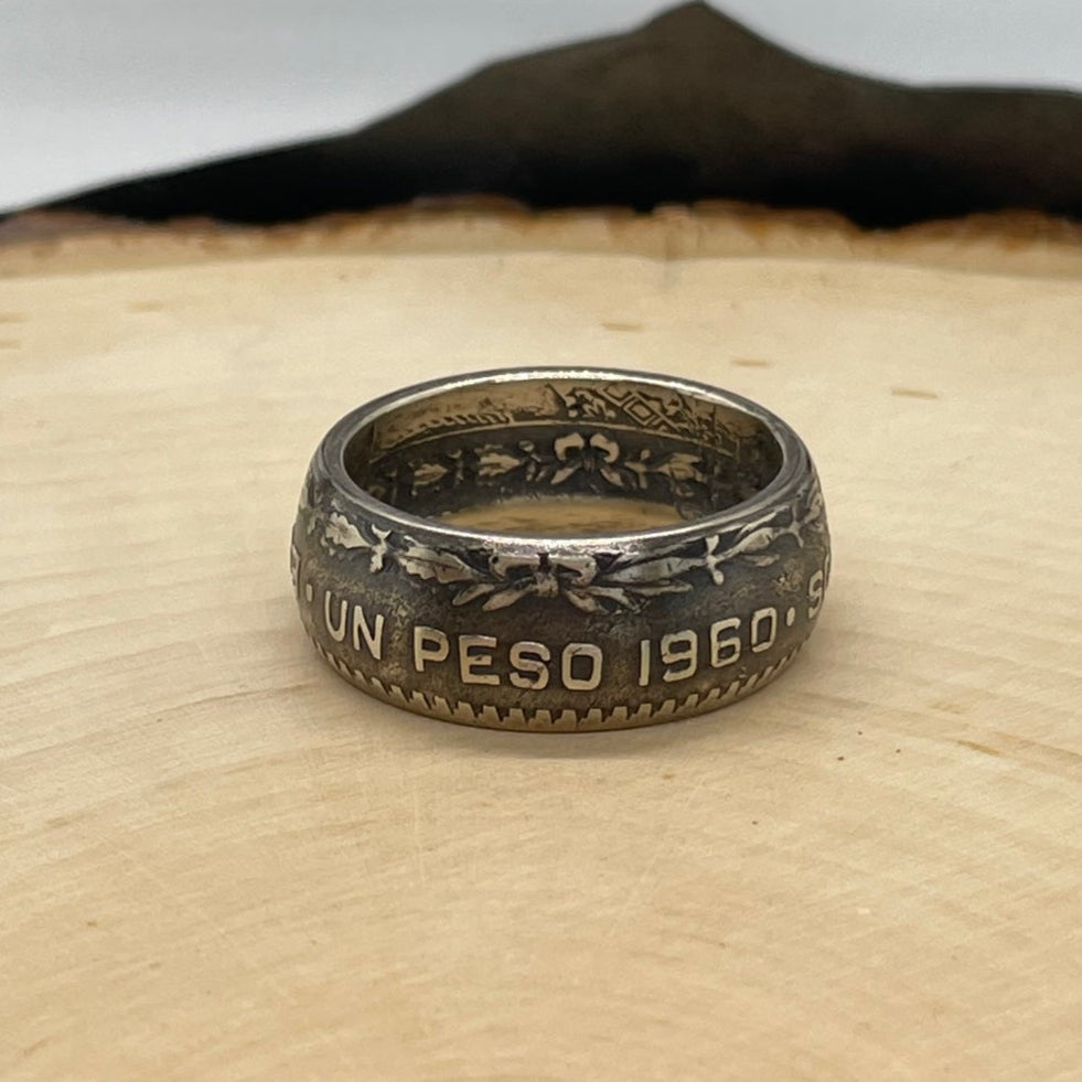 Mexico Silver Peso Coin Ring on a light wood round with mountain outline in the background. - Mountainstruck Coin Jewelry