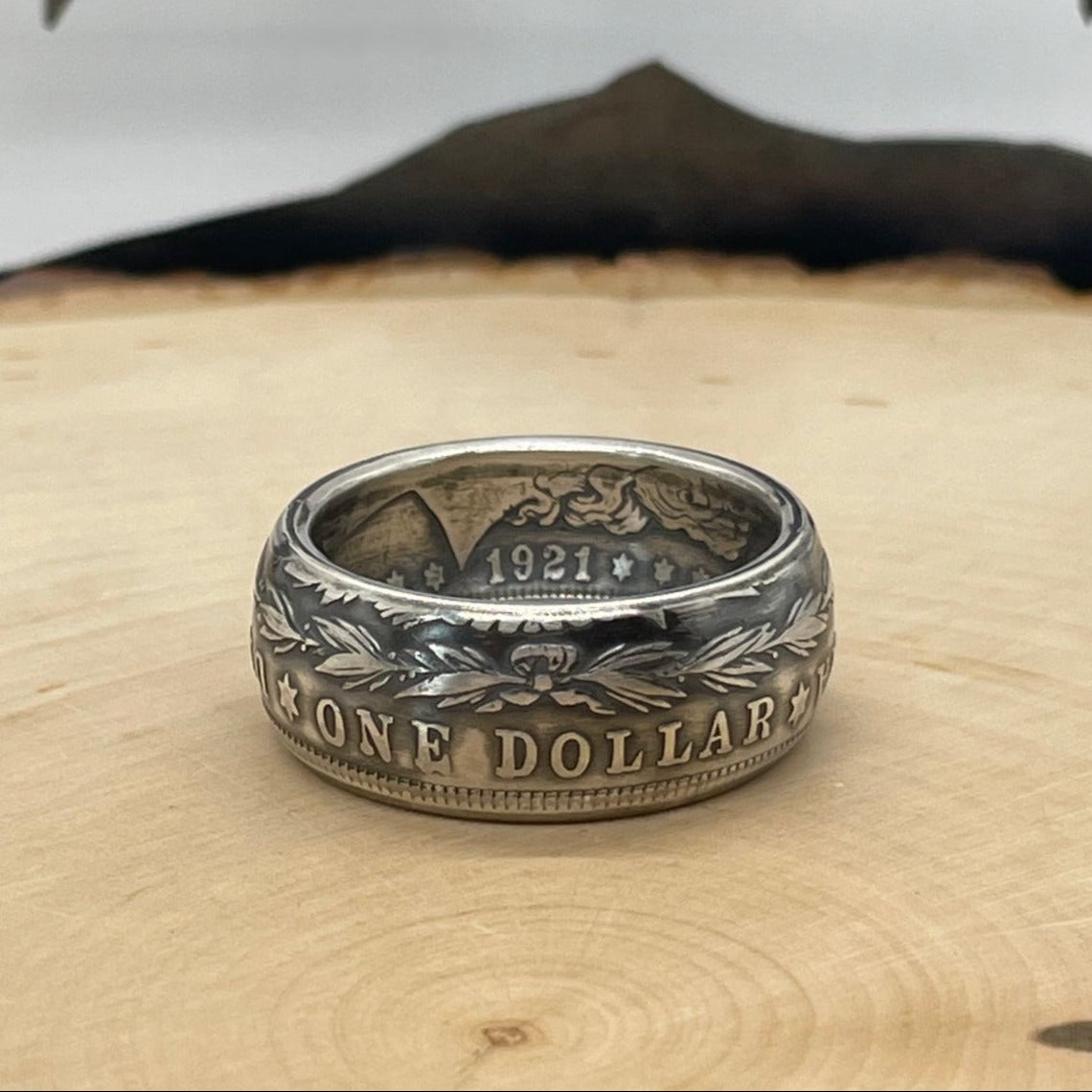 Morgan Dollar Silver Coin Ring on a light wood round with mountain outline in the background. - Mountainstruck Coin Jewelry