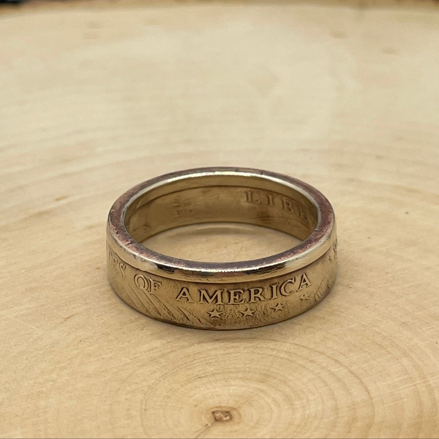 Sacagawea Dollar Coin Ring on a light wood round with mountain outline in background. - Mountainstruck Coin Jewelry