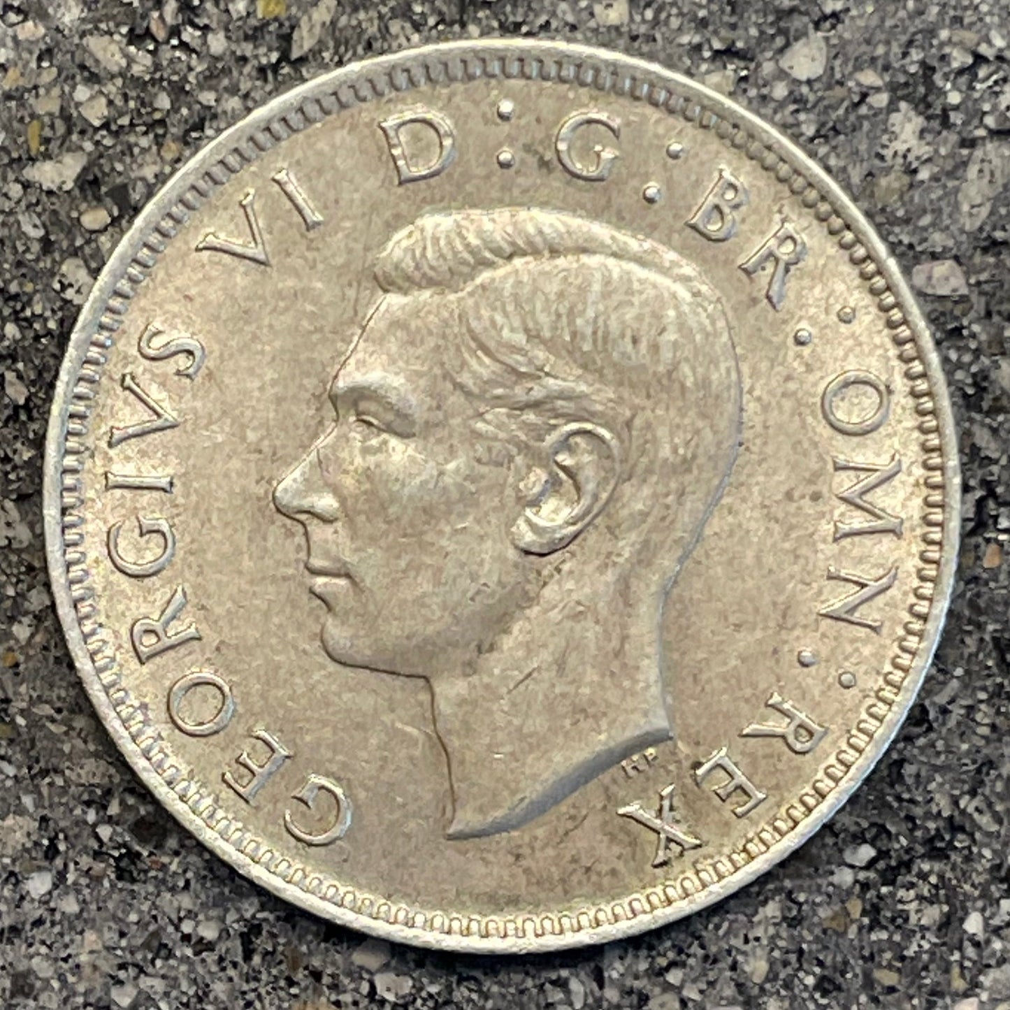 UK Two Shillings Silver Coin front on a concrete background.