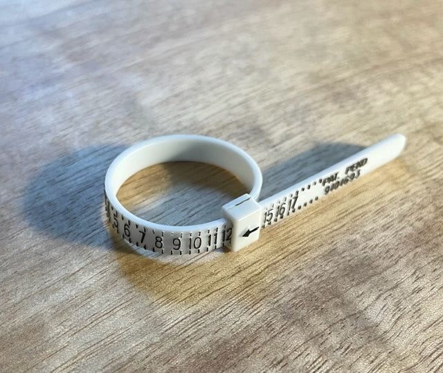 Plastic Adjustable Ring Sizer on a wood background. - Mountainstruck Coin Jewelry