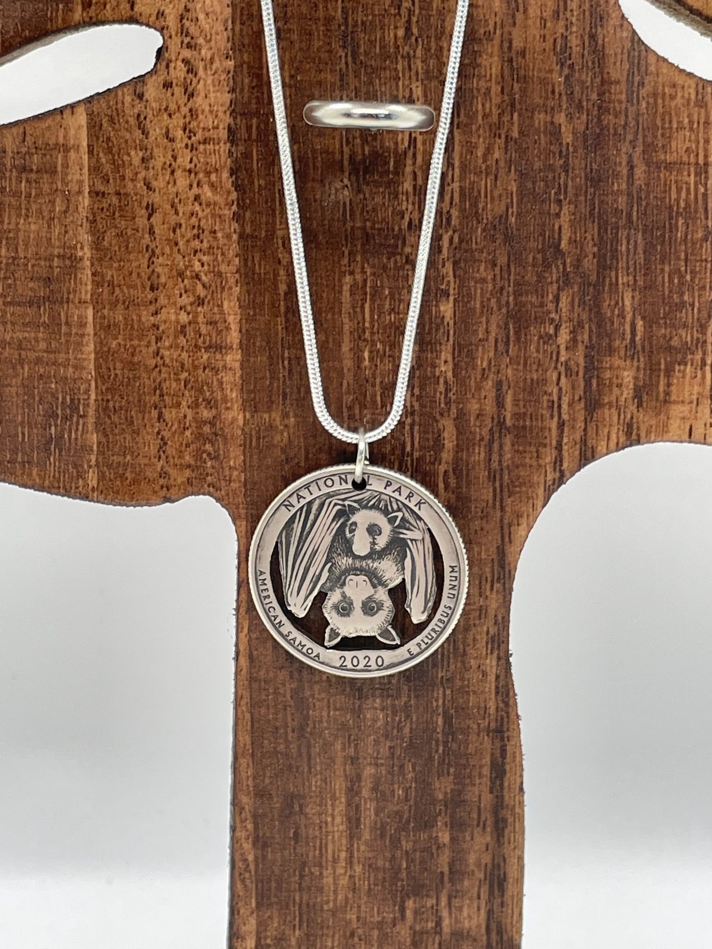 U.S. American Samoa National Park US Quarter Coin Necklace (Bats!) on a wooden tree background.