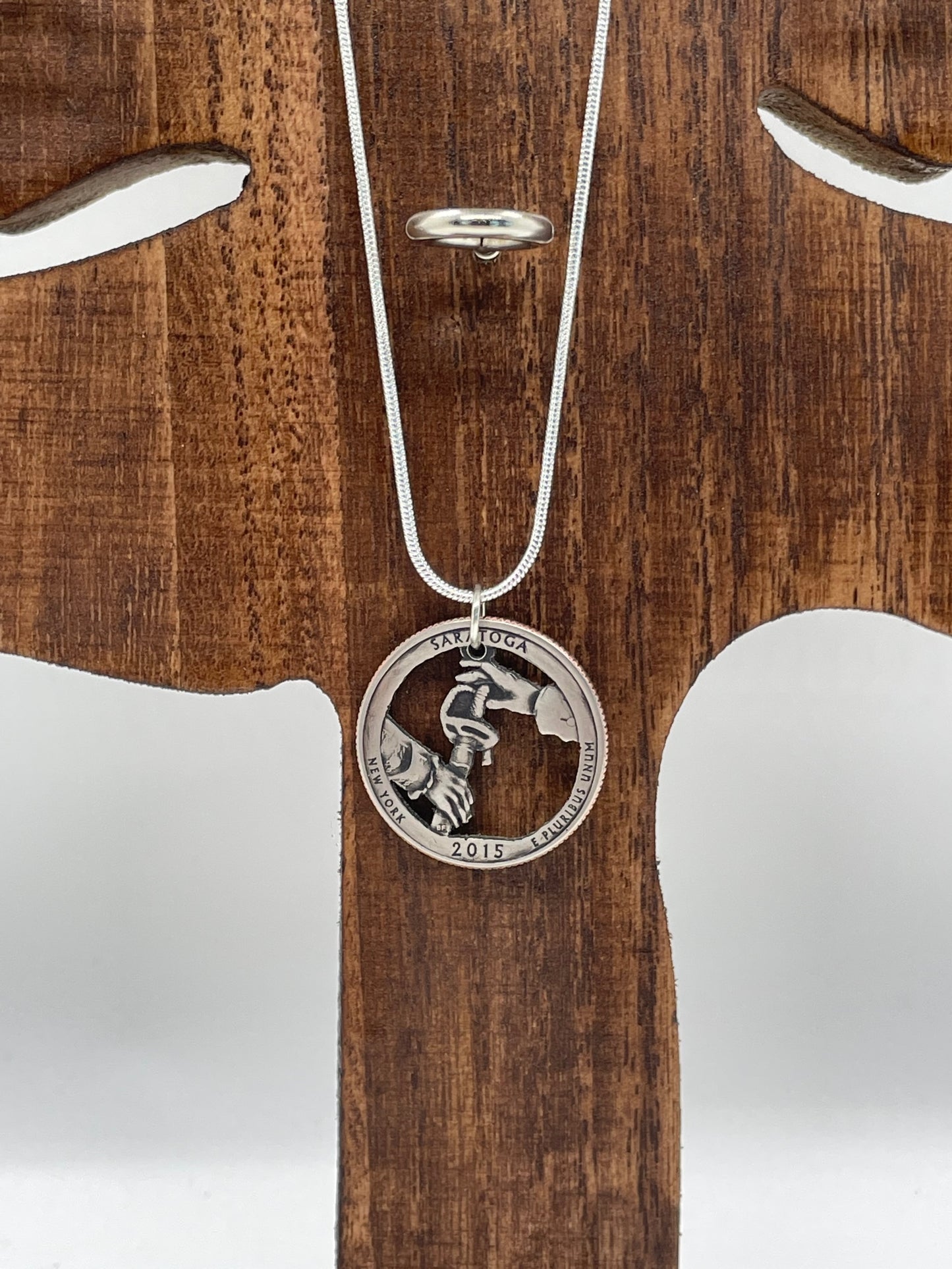 U.S. Saratoga British Surrender Hand Cut Coin Necklace on wood tree display.