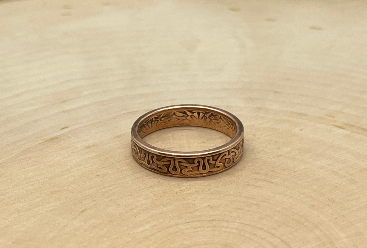 Suriname 1 Cent Coin Ring on a light wood round.