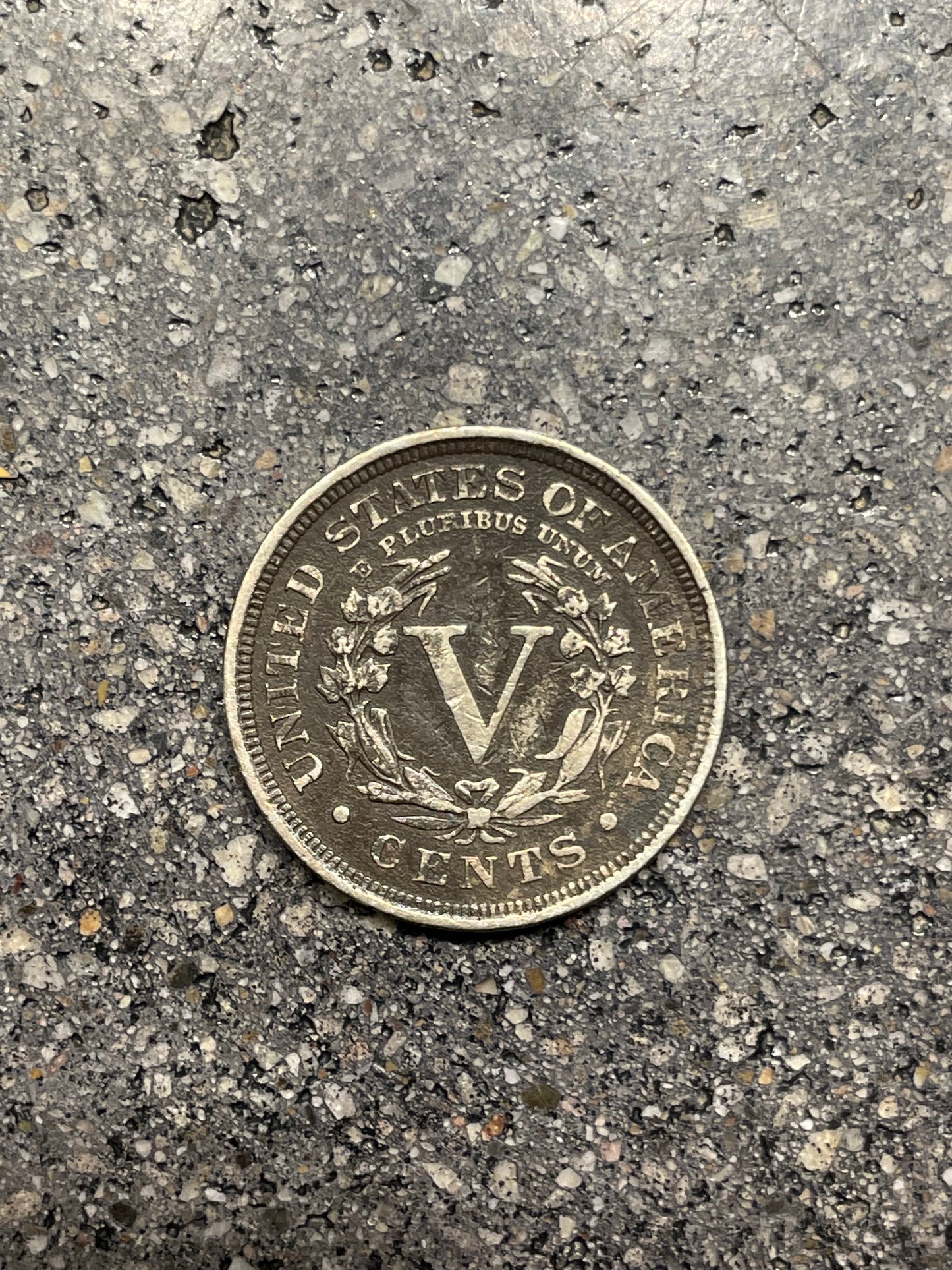 "V" Nickel coin backside on concrete background.
