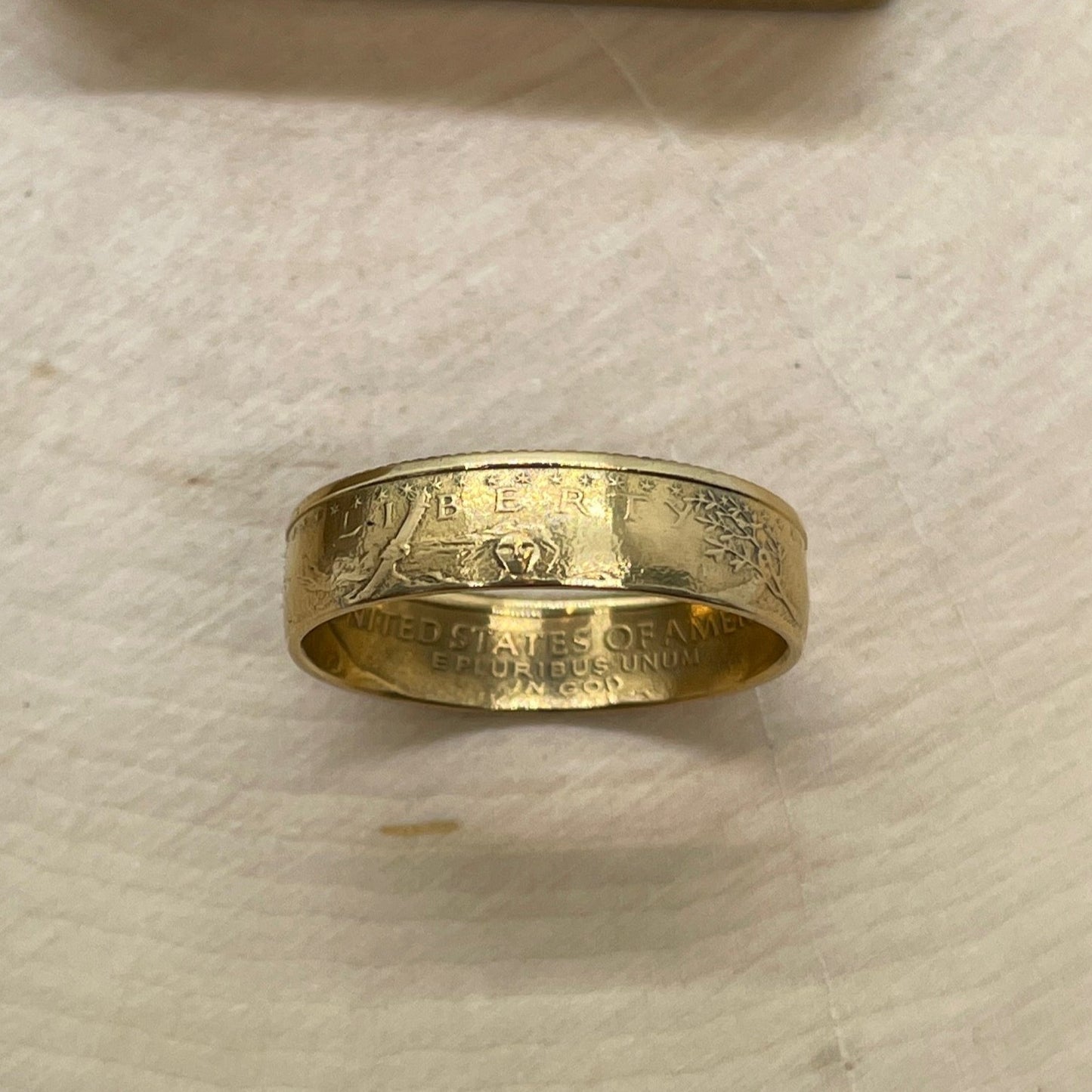 U.S. Gold Eagle 1/4 oz Fine Gold Coin Ring on its edge on a light wood round.