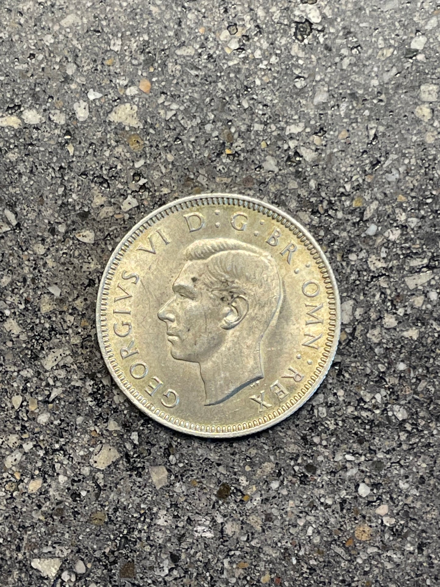 UK One Shilling Silver Coin front on a concrete background.