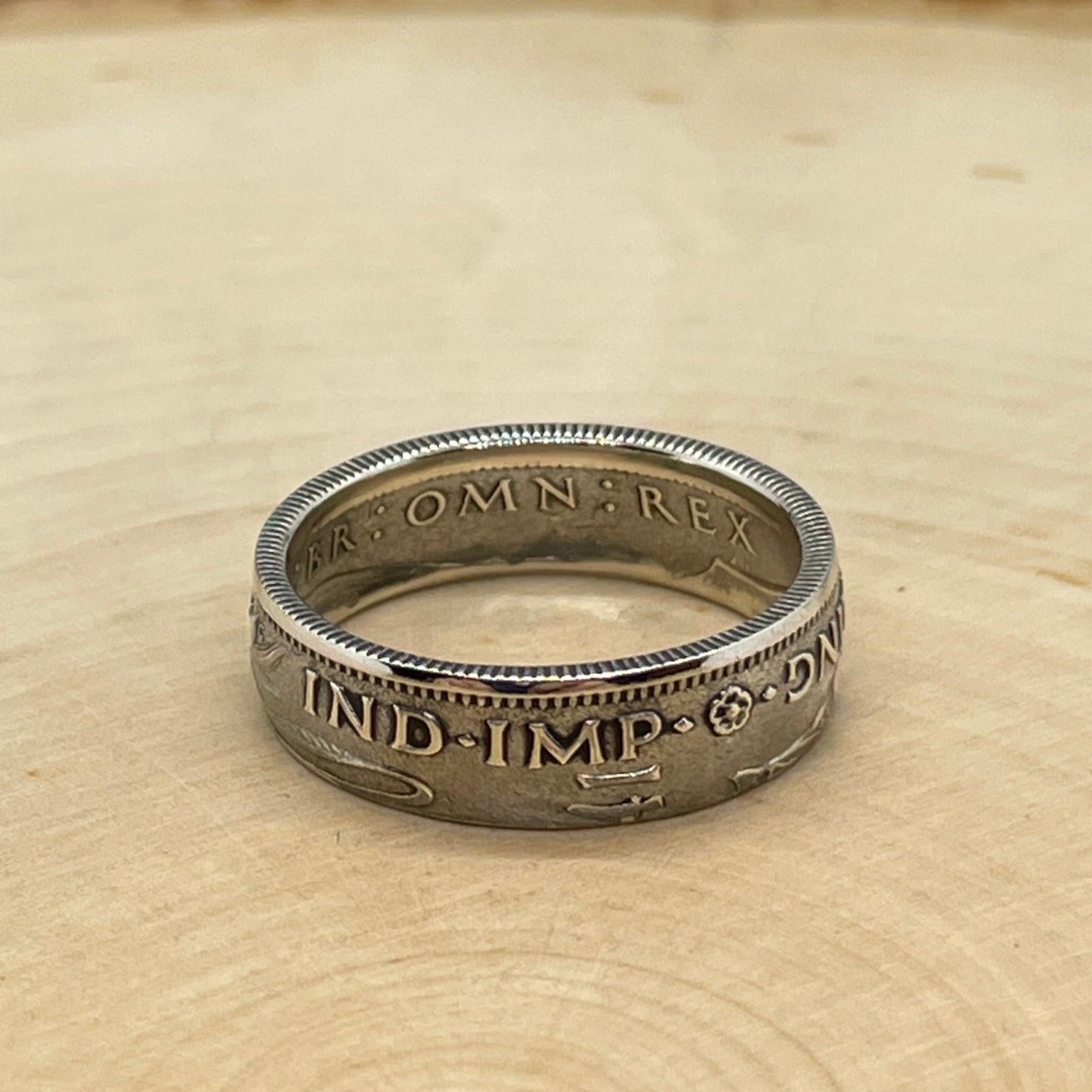 UK One Shilling Silver Coin Ring on a light wood round.