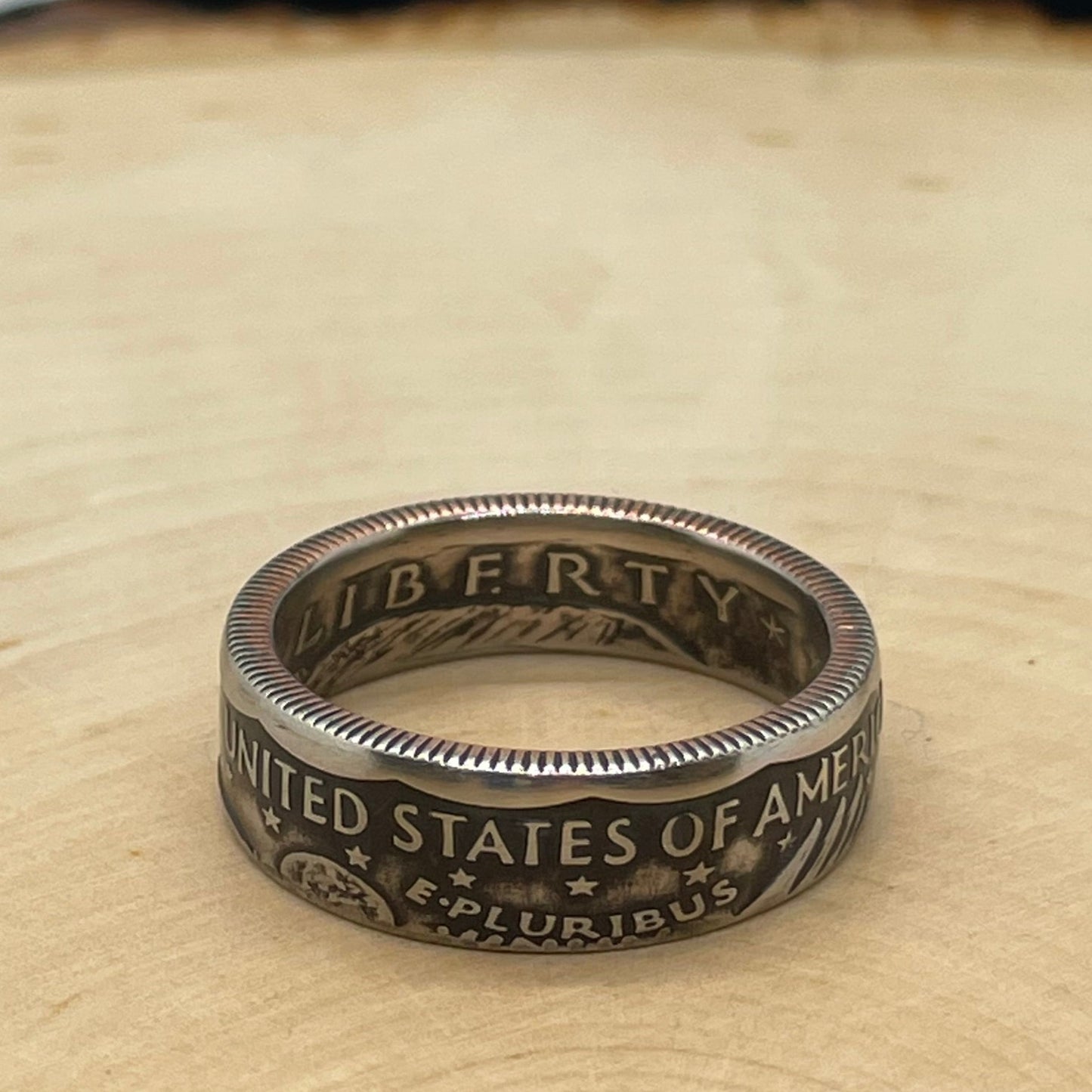 Susan B. Anthony Dollar Coin Ring on a light wood round.