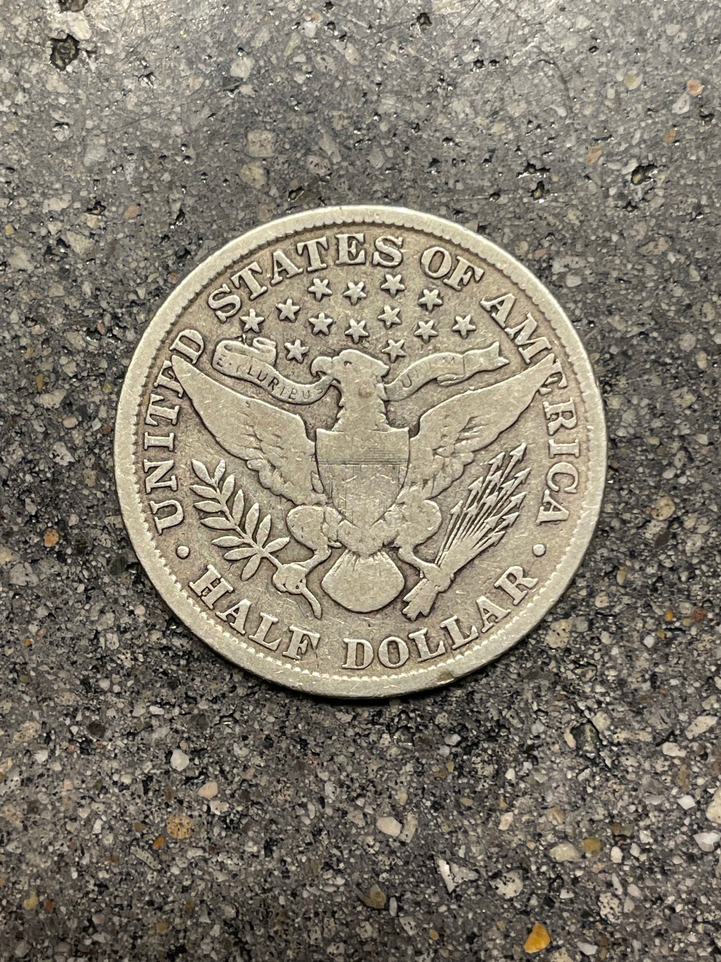 Barber Silver Half Dollar back of coin on a concrete background.