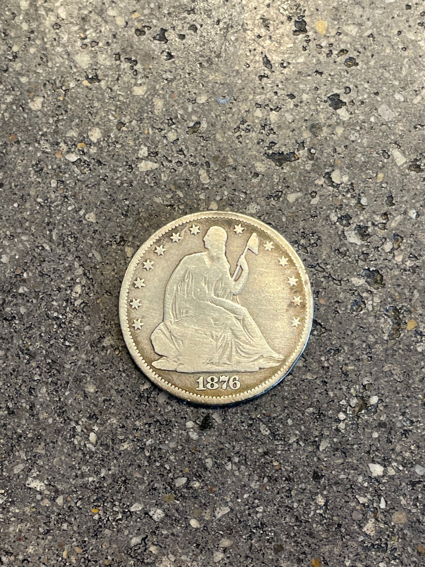 Seated Liberty Silver Half Dollar Coin front on a concrete background.