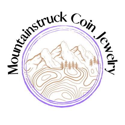 Logo of Mountainstruck Coin Jewelry with mountain and tree design. - Mountainstruck Coin Jewelry