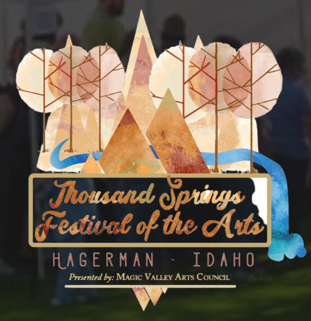 Promotional graphic for the Thousand Springs Festival of the Arts in Hagerman, Idaho, presented by the Magic Valley Arts Council. The design features a stylized watercolor illustration of mountains, trees, and a river in muted beige, brown, and blue tones, with gold lettering on a black banner. -Mountainstruck Coin Jewelry 