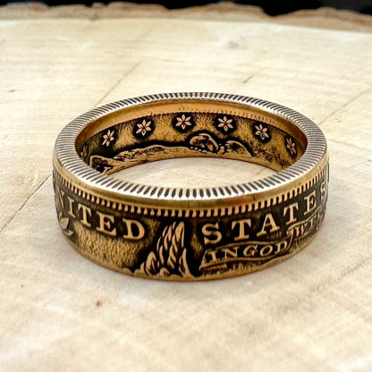 22k U.S. Gold Eagle $10 Coin Ring on a light wood round with a metal mountain background. - Mountainstruck Coin Jewelry