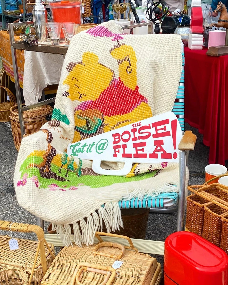 Vintage items including a chair with a Winnie the Pooh design and a red cool with a wooden microphone shaped sign saying "Get it @ the Boise Flea!". - Mountainstruck Coin Jewelry