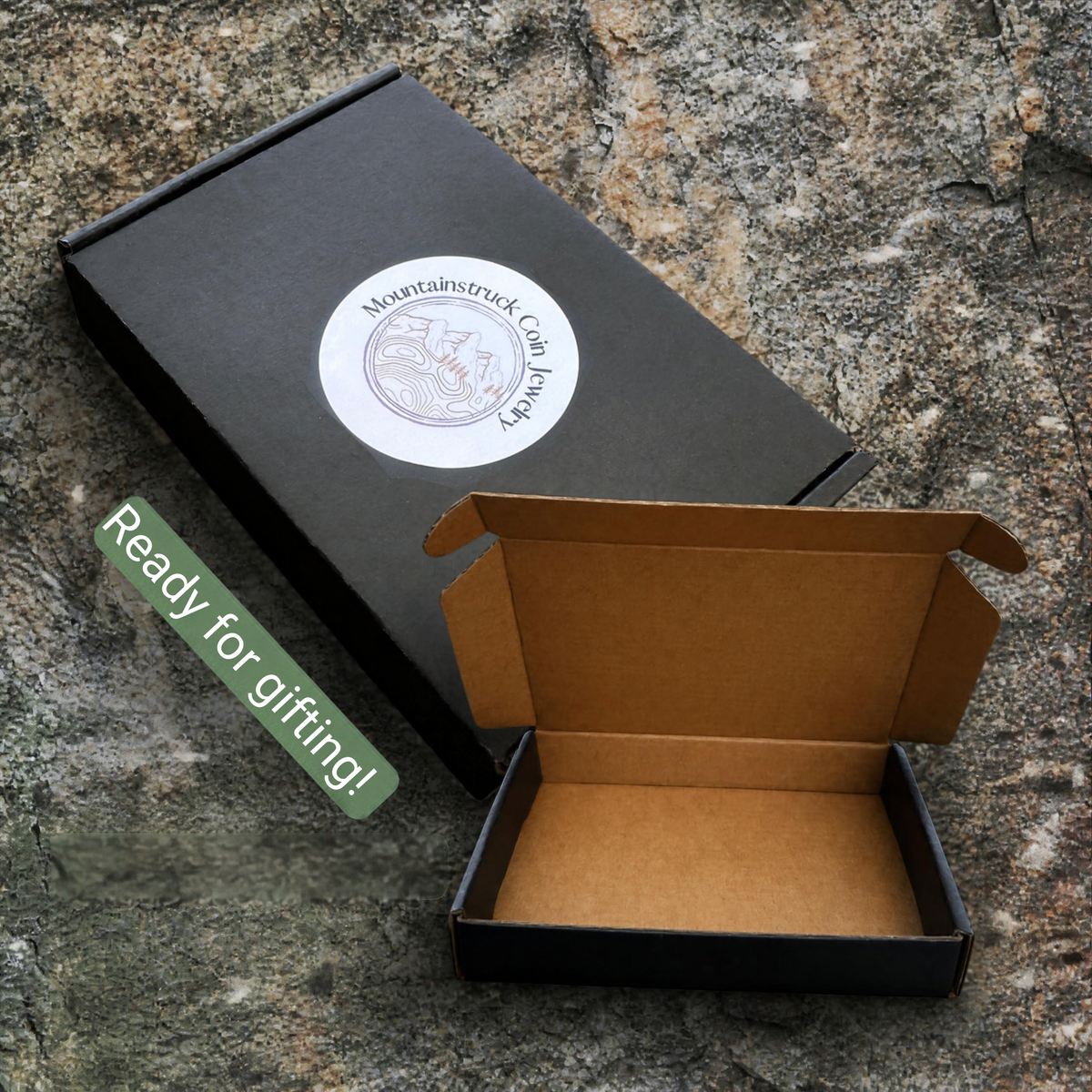 Bolo tie black cardboard gift box on a textured rock background. - Mountainstruck Coin Jewelry