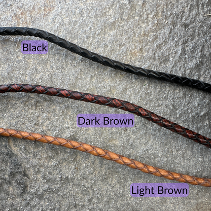 Bolo tie braided leather cord color options (black, Dark Brown, & Light Brown) on a textured rock background. - Mountainstruck Coin Jewelry
