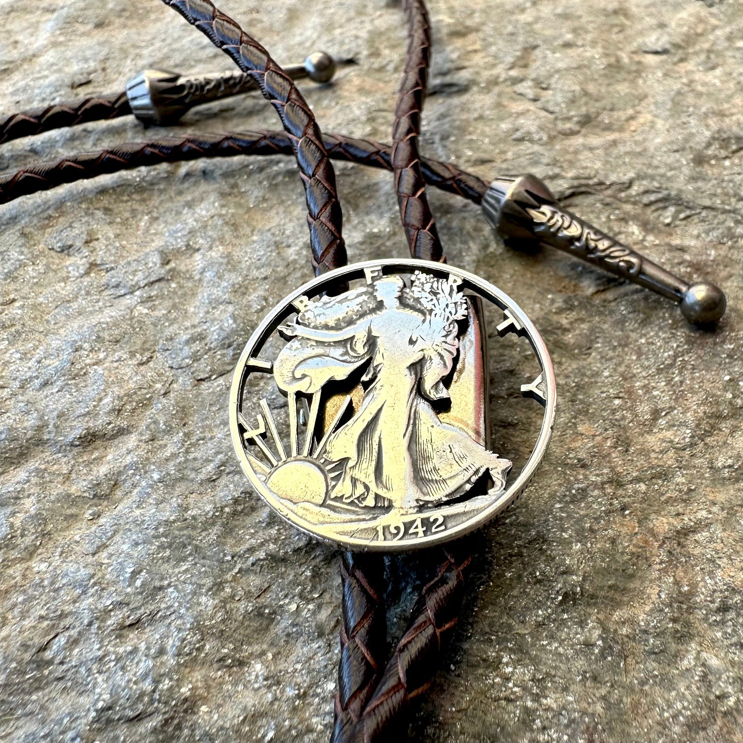 U.S. Walking Liberty Half Dollar Hand Cut Silver Coin Bolo Tie on a grey rock surface. - Mountainstruck Coin Jewelry