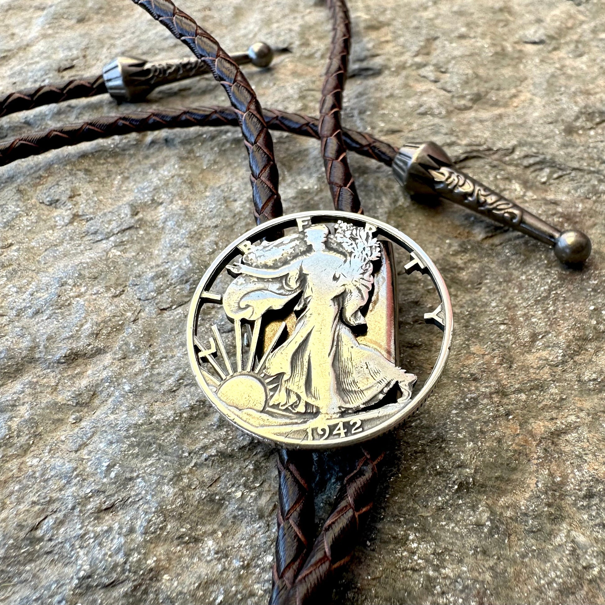 U.S. Walking Liberty Half Dollar Hand Cut Silver Coin Bolo Tie on a grey rock surface. - Mountainstruck Coin Jewelry