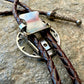 U.S. Walking Liberty Half Dollar Hand Cut Silver Coin Bolo Tie back on a grey rock surface.- Mountainstruck Coin Jewelry