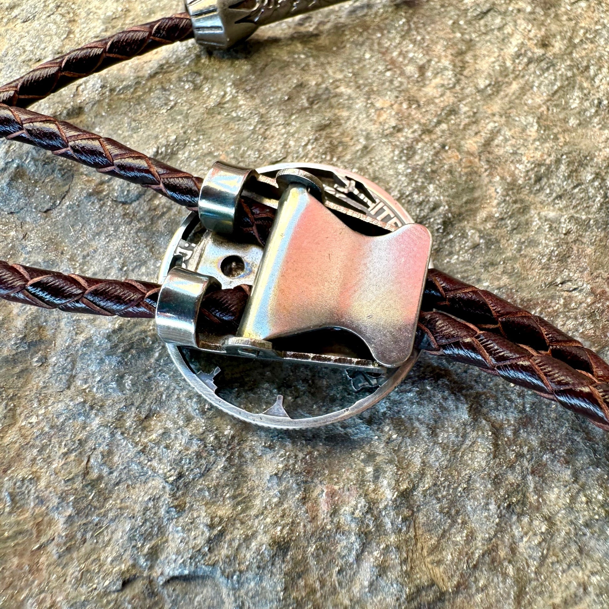 U.S. Walking Liberty Half Dollar Hand Cut Silver Coin Bolo Tie back on a grey rock surface. - Mountainstruck Coin Jewelry