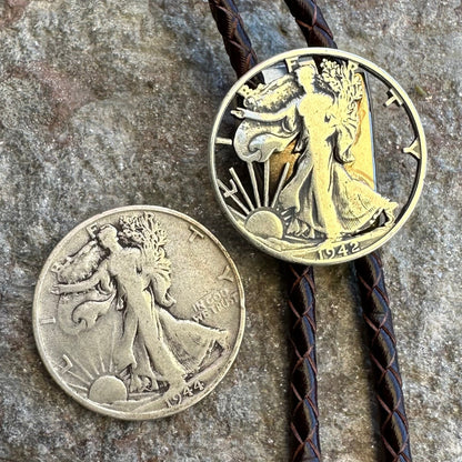 U.S. Walking Liberty Half Dollar Hand Cut Silver Coin Bolo Tie with half dollar coin uncut to the left on a grey rock surface. - Mountainstruck Coin Jewelry