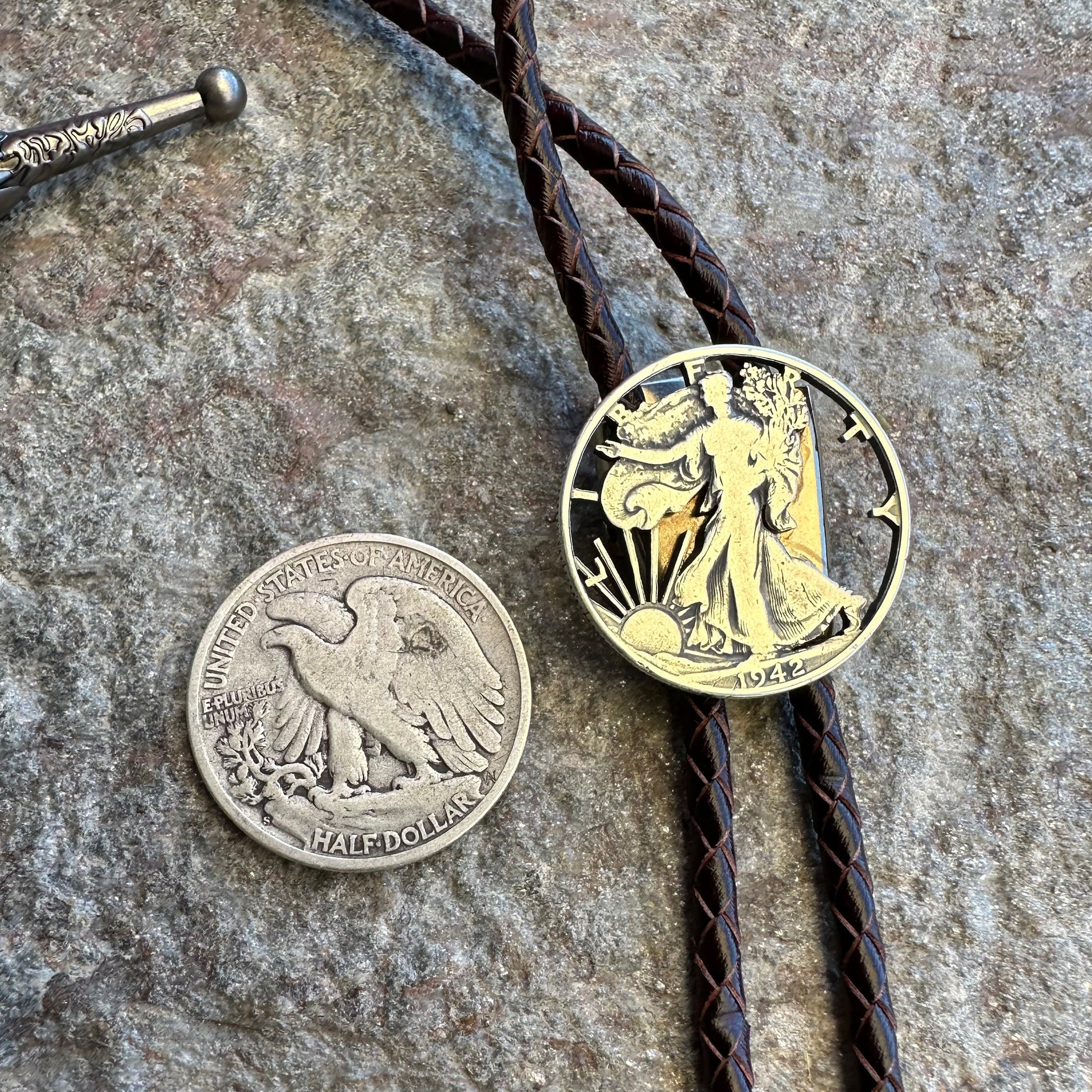 U.S. Walking Liberty Half Dollar Hand Cut Silver Coin Bolo Tie with coin back to left on a grey rock surface. - Mountainstruck Coin Jewelry