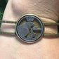 Idaho State Quarter Cut Out Coin in a bronze bracelet on a wrist in front of a pine tree. - Mountainstruck Coin Jewelry