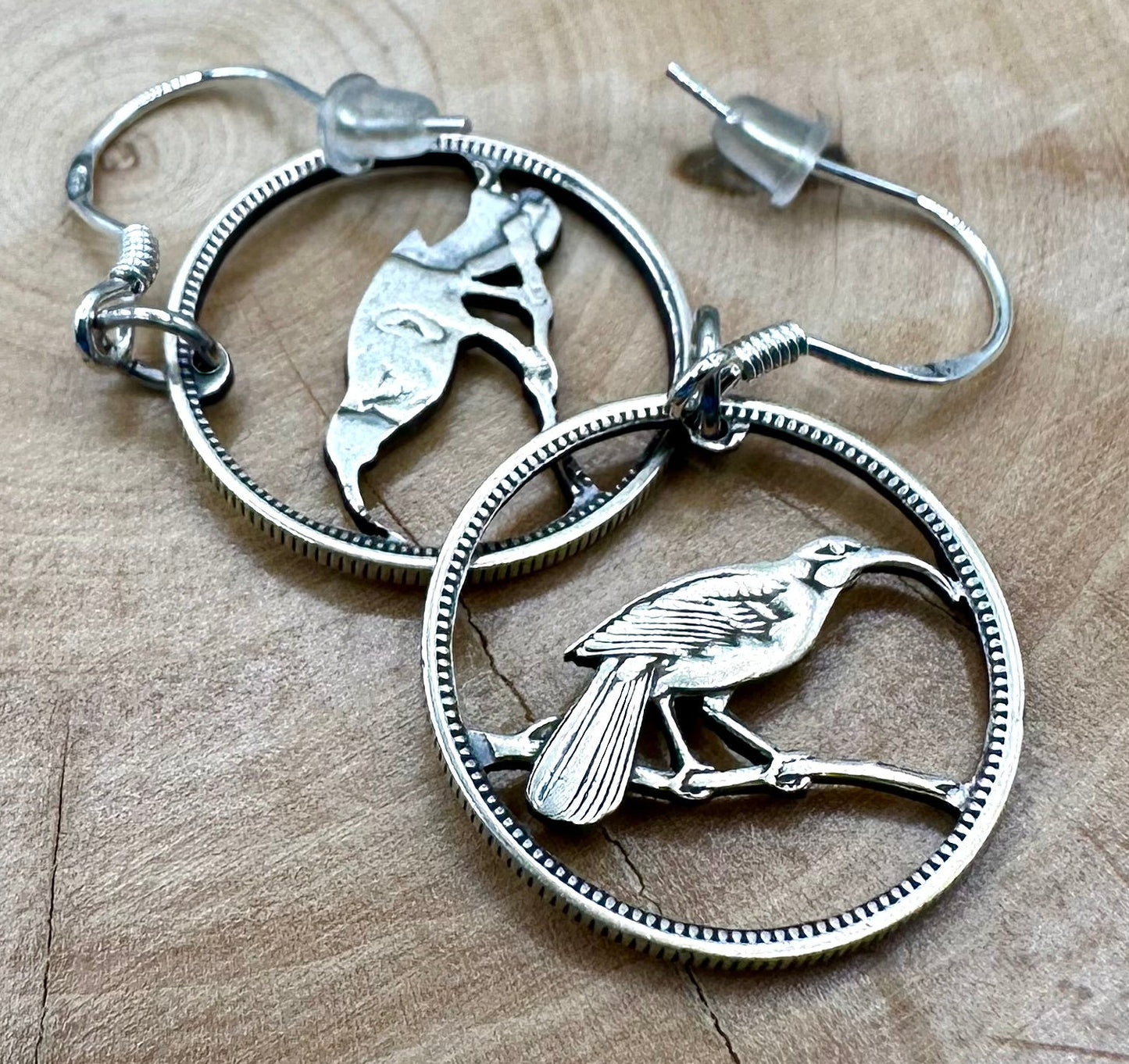 New Zealand Huia Bird 6 Pence Silver Hand Cut Coin Earrings on a light wood background. - Mountainstruck Coin Jewelry