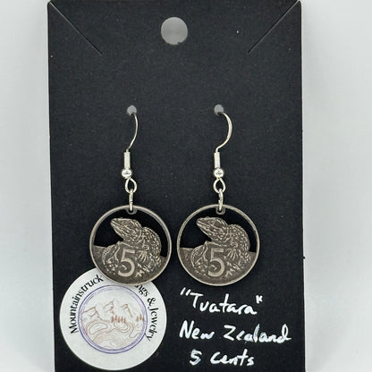 Tuatara New Zealand 5 Cents Hand Cut Coin Earrings on a black background with a round Mountainstruck Coin Jewelry sticker in bottom left corner.