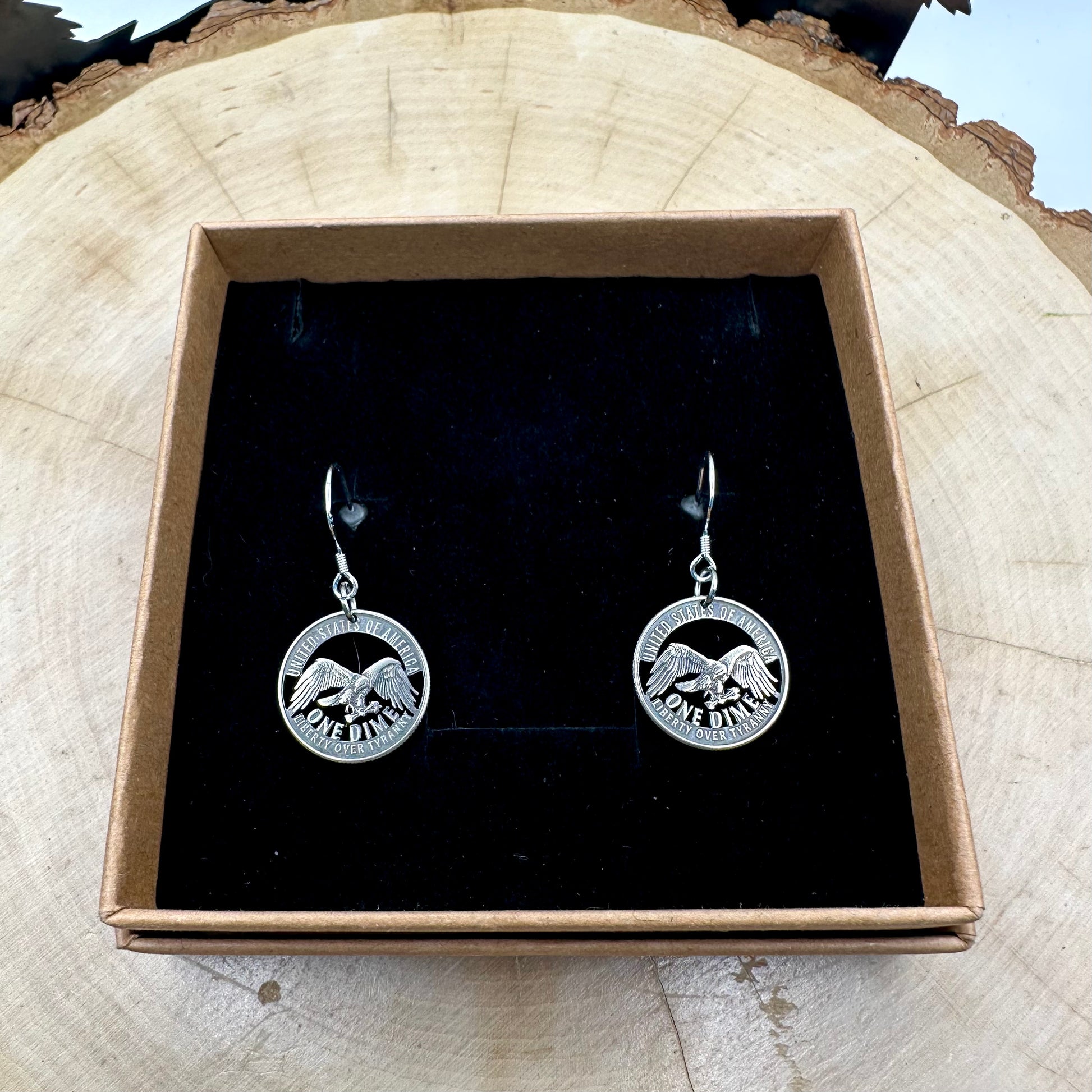 U.S. 2026 "Liberty over Tyranny" Dime Hand Cut Coin Earrings on a black velvet background in a brown kraft box on a wood round. -Mountainstruck Coin Jewelry