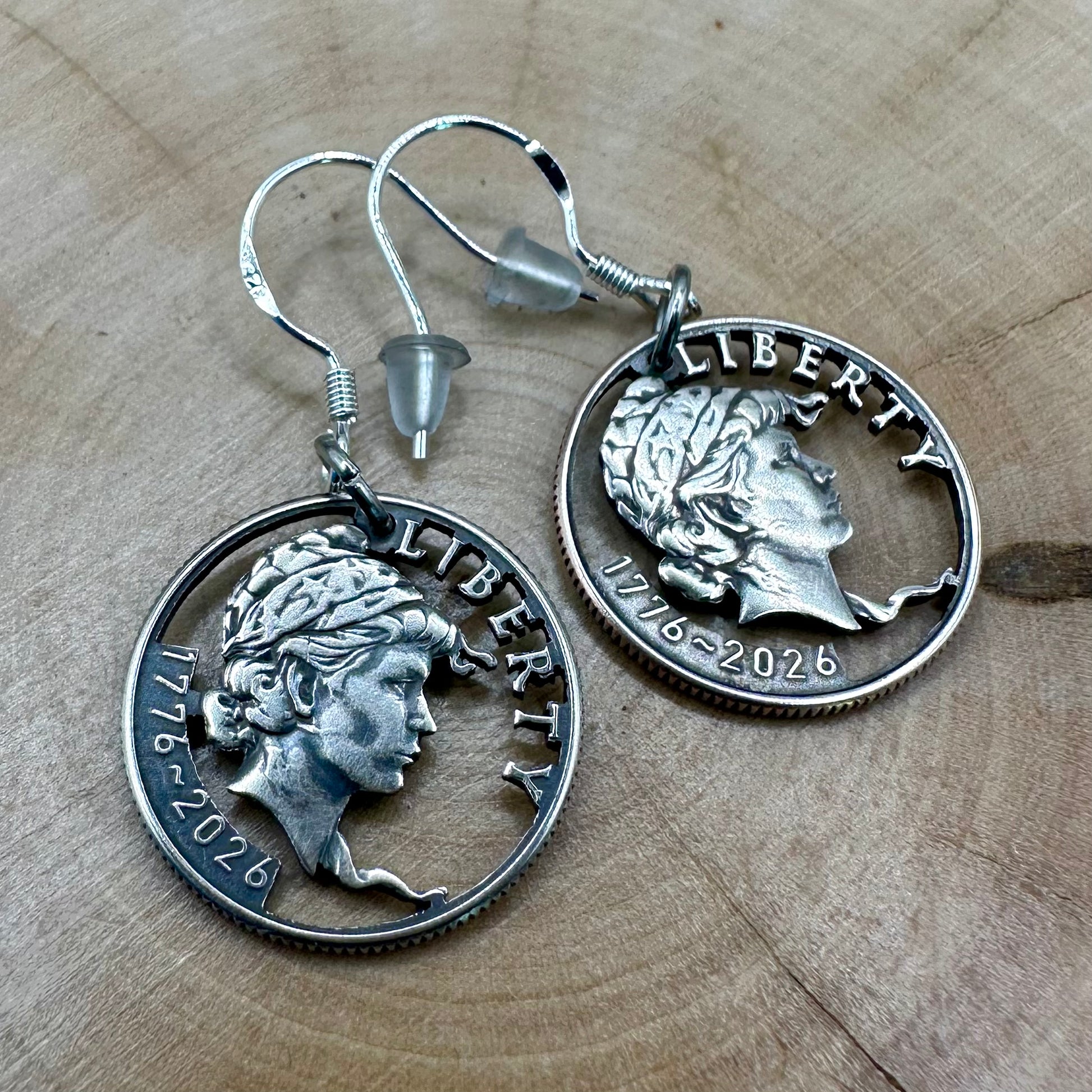 U.S. 2026 "Lady Liberty" Dime Hand Cut Coin Earrings on a wood round. -Mountainstruck Coin Jewelry
